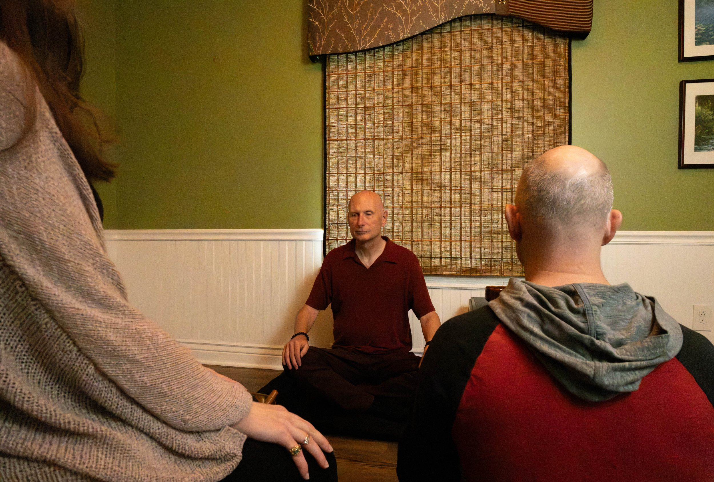 Image of John and two others meditating in a group setting.