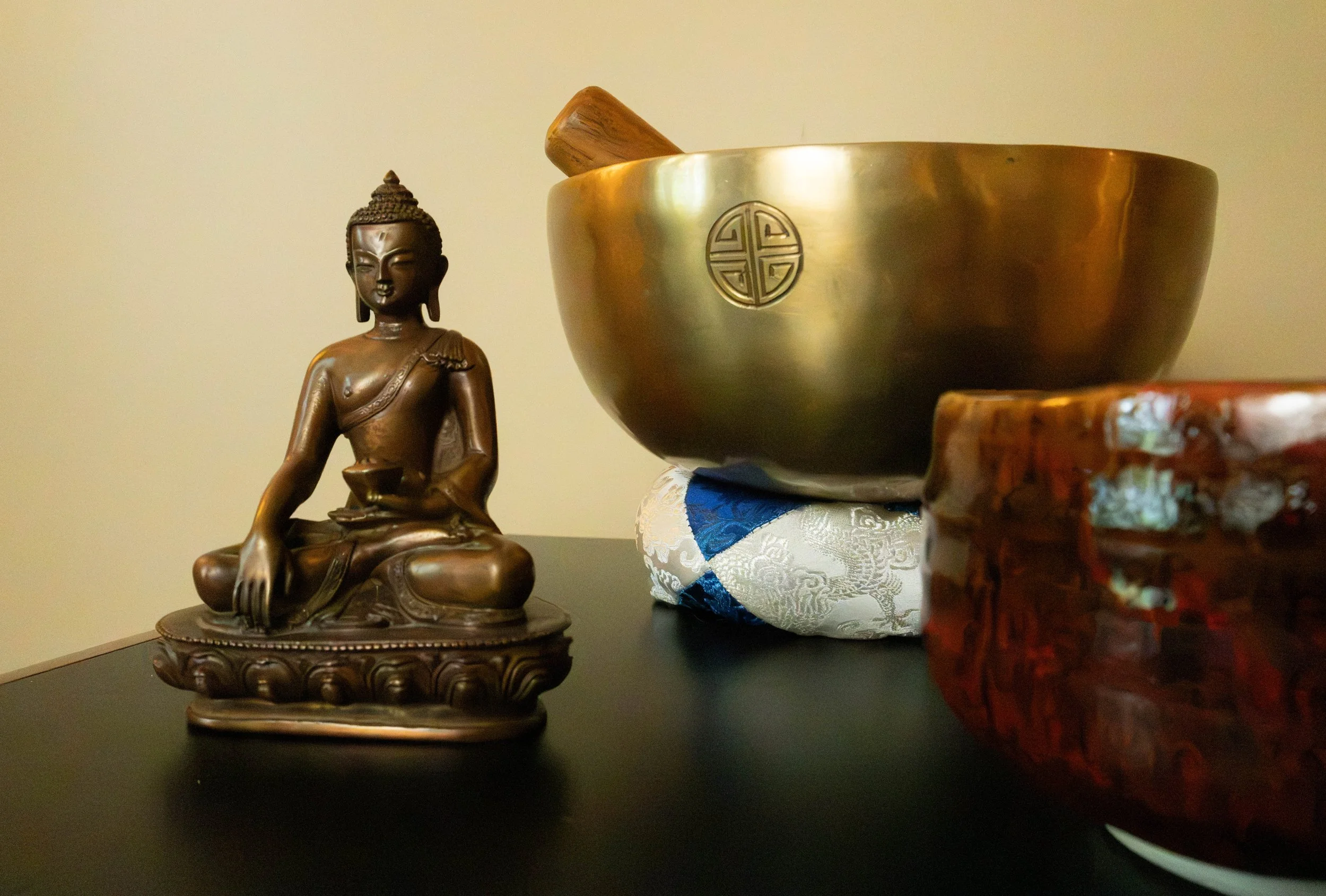 Image showing a table with a small statue of the Buddha, a chime bowl, and an incense bowl.