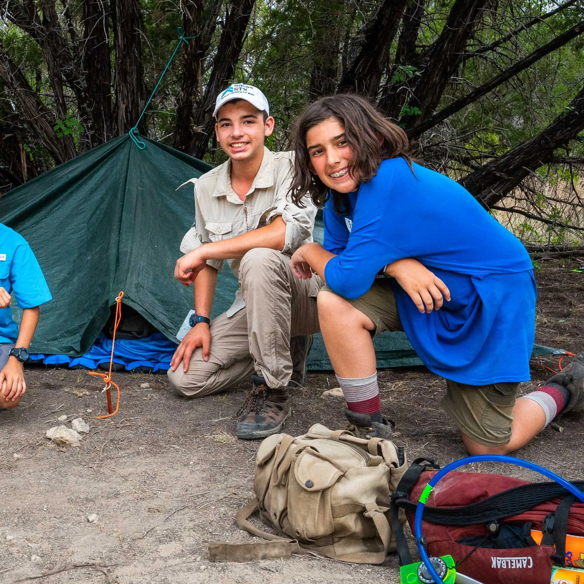 Two smiling boys by their tarp shelter