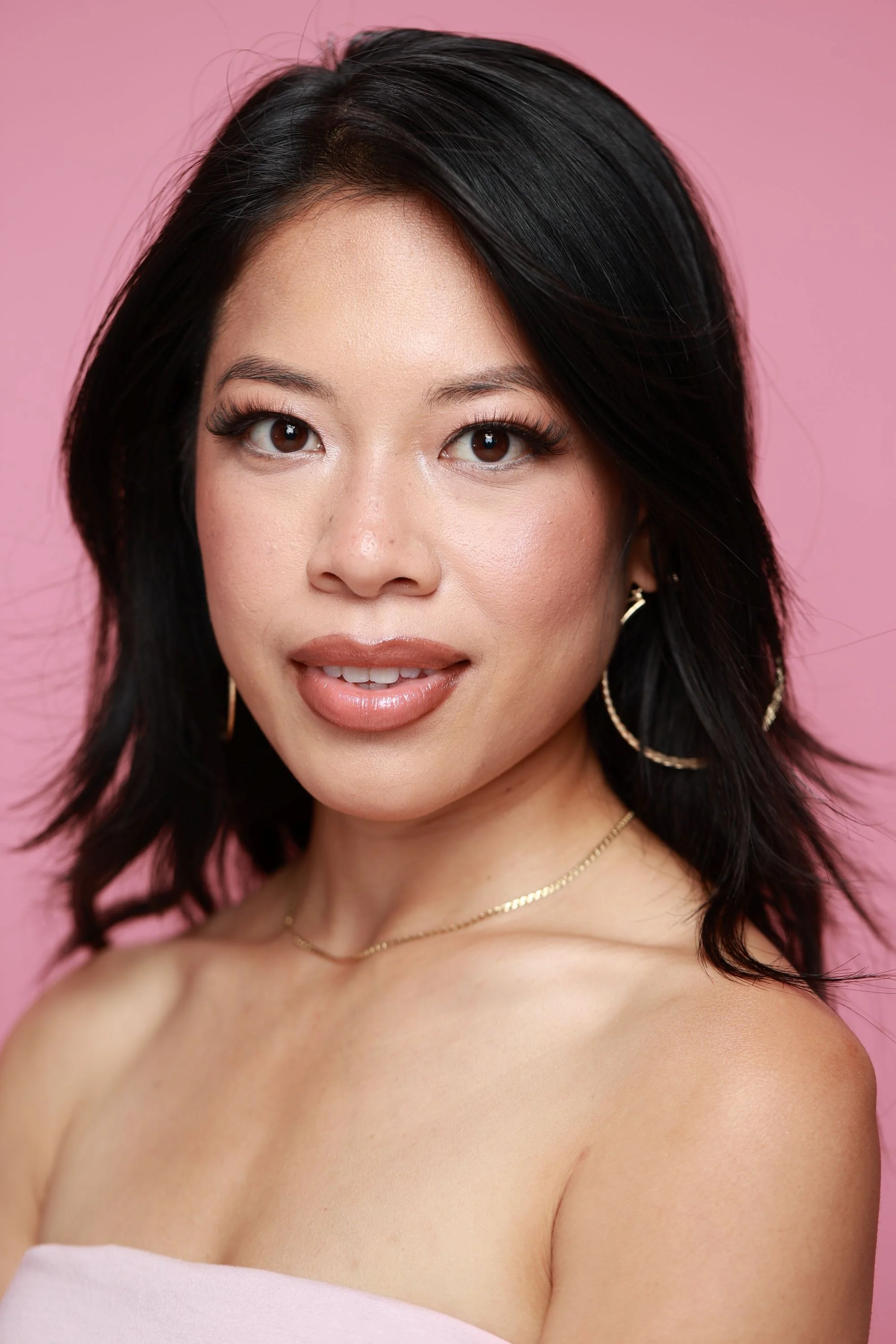 Model with dark hair and large hoop earrings wearing Dream Lip Gloss