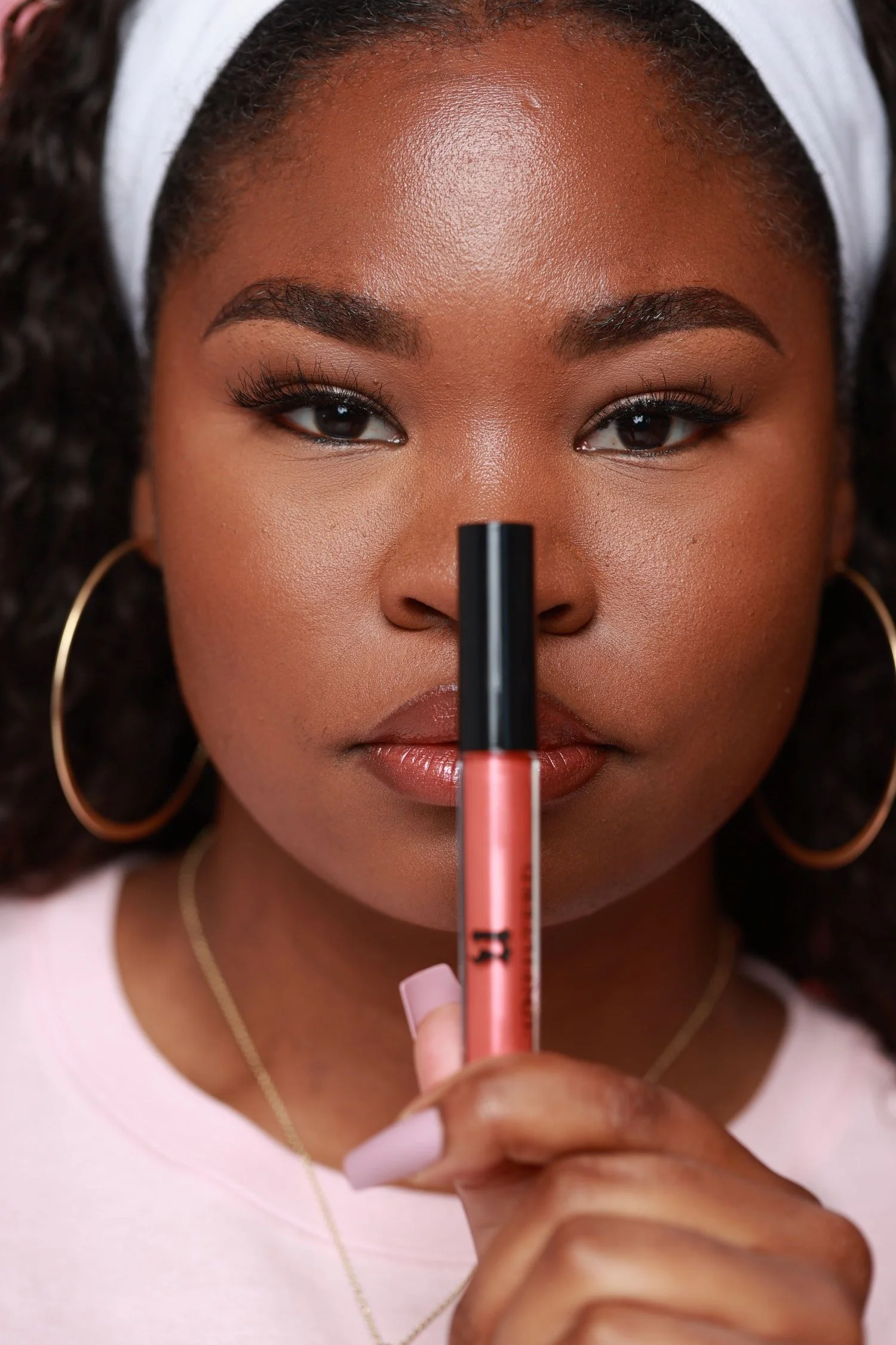 Model wearing and holding to face Tropical Tease Lip Gloss.
