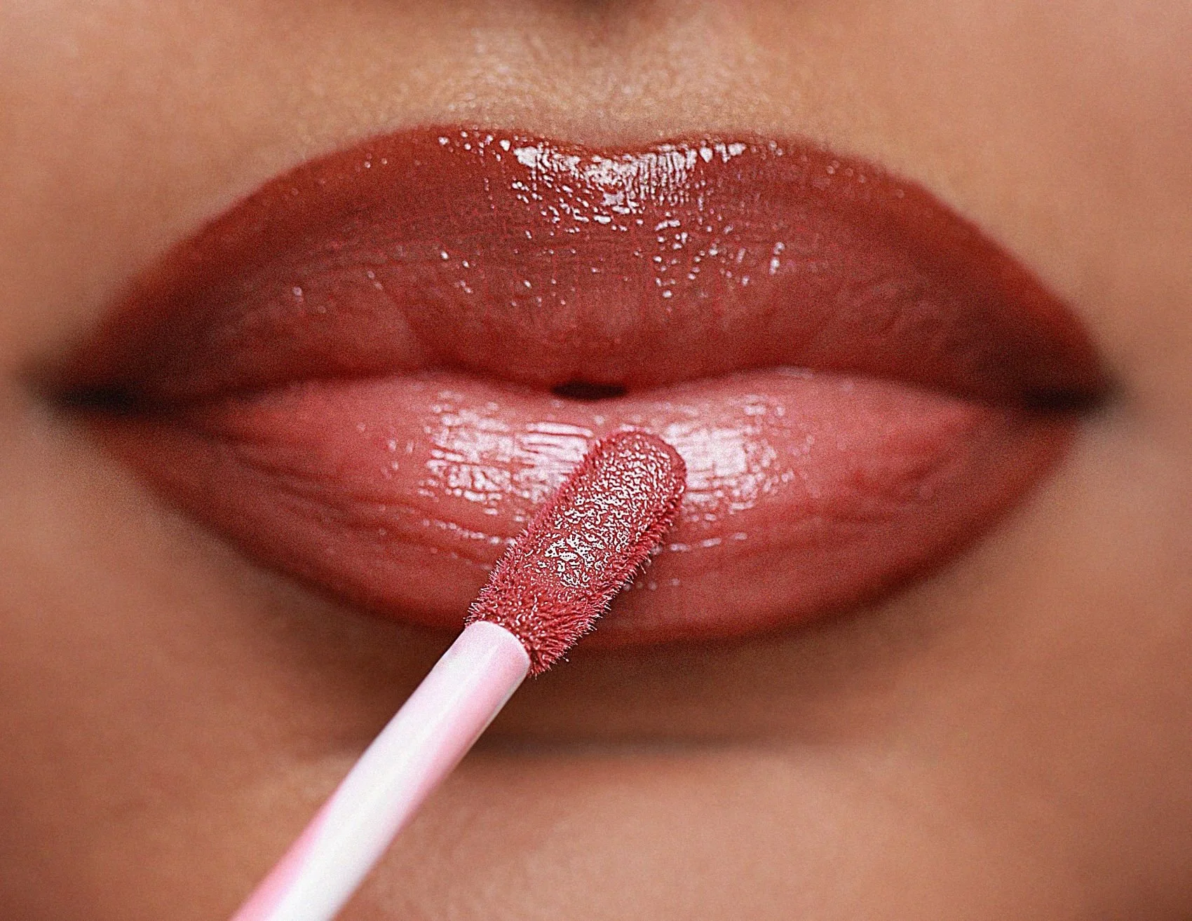 Close up of Plush lip gloss being applied to  lips.