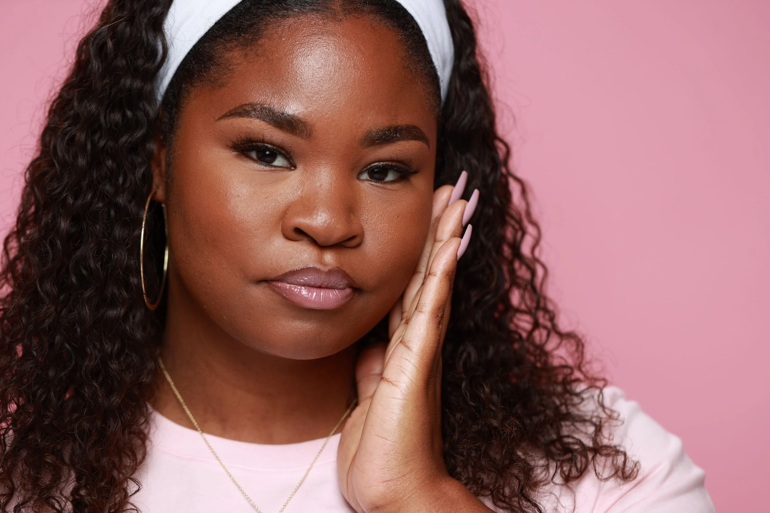 Model with hand to face wearing Sweet Lip Gloss