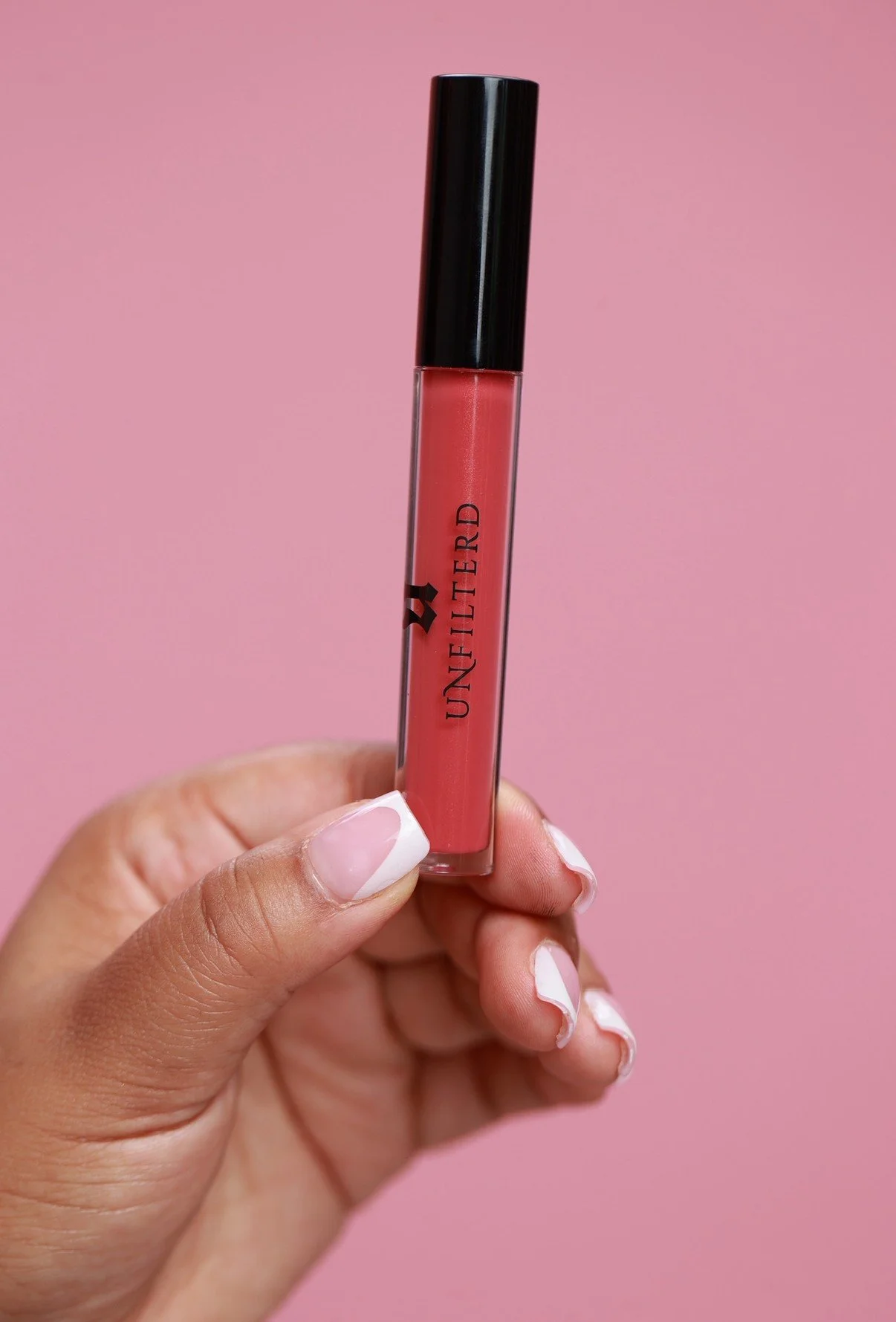 Hand with modern French Tip Manicure holding Plush Lip Gloss