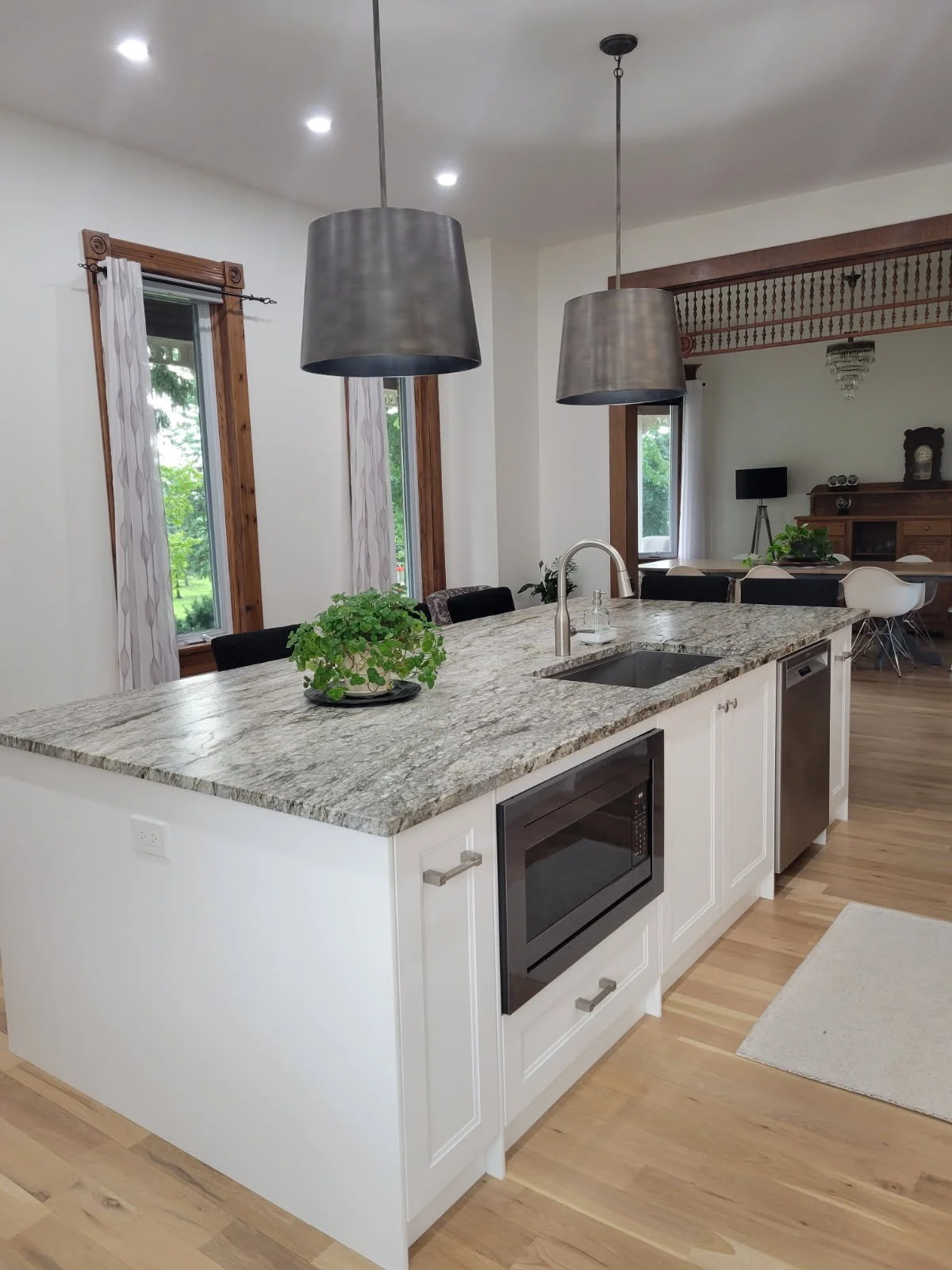 The kitchen island brings the sink, dishwasher and built-in microwave together, with seating on the other side.
