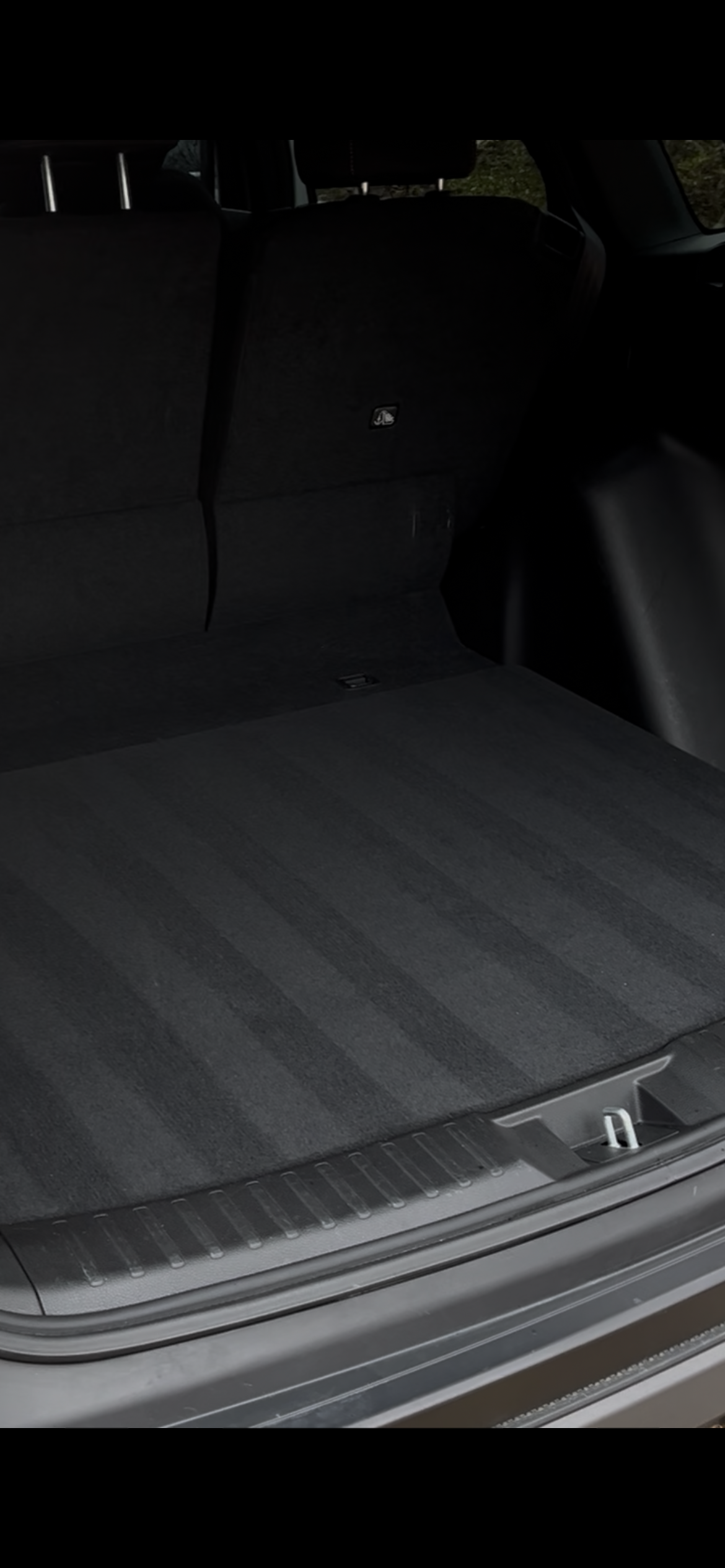 The trunk of a vehicle with a black carpeted cargo area and a metal load lip near the entrance.
