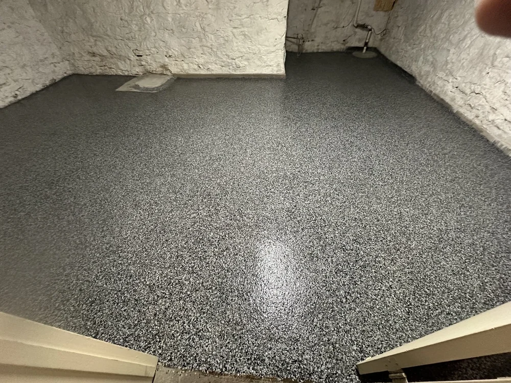 Dark decorative-chip floor bordered by stone walls and a doorway in a Brookside basement