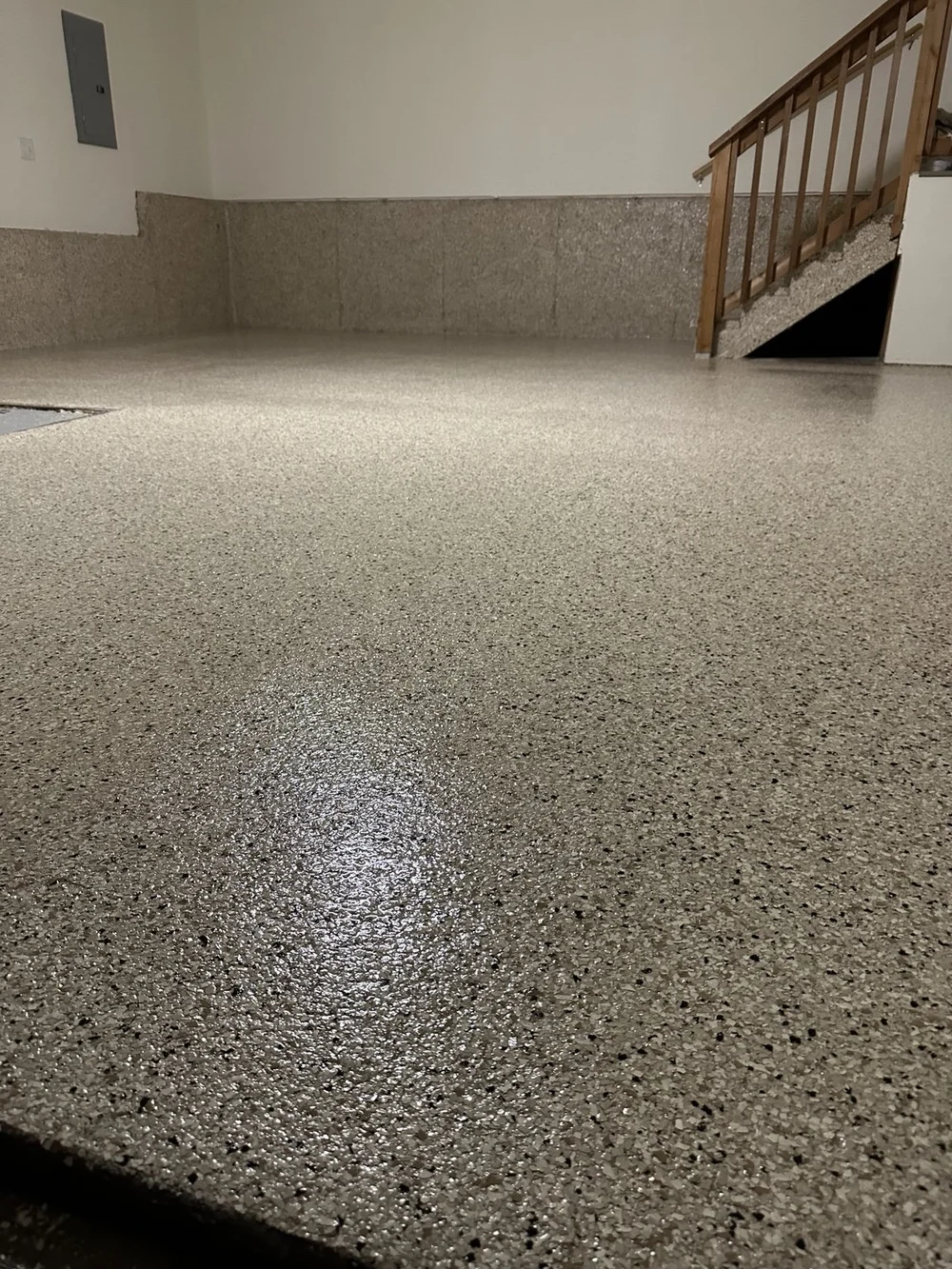 Decorative-chip floor and coated wall bases beside wooden stairs in a Leawood garage