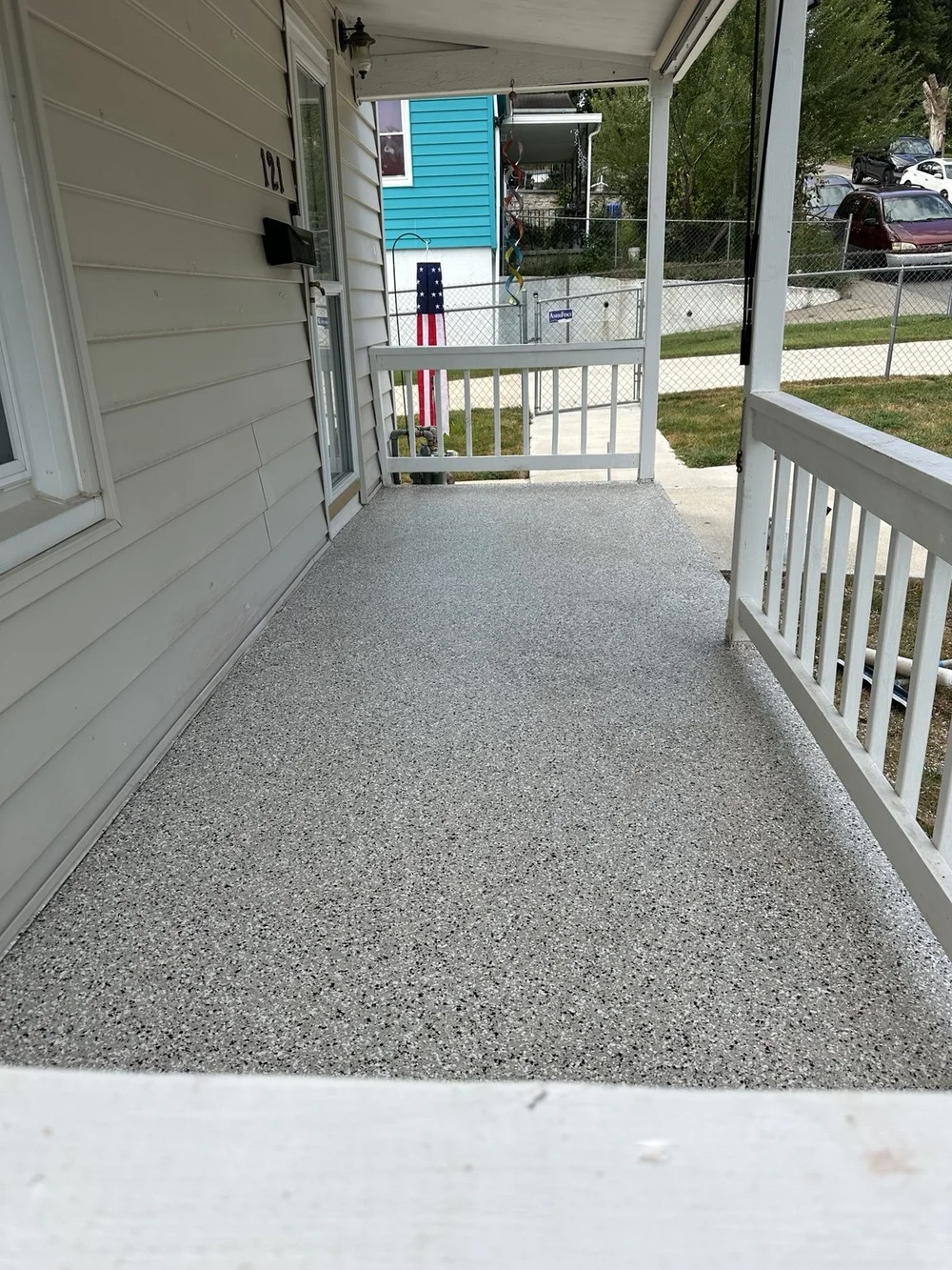 Finished decorative-chip floor on a covered Kansas City, Kansas porch beside white railing