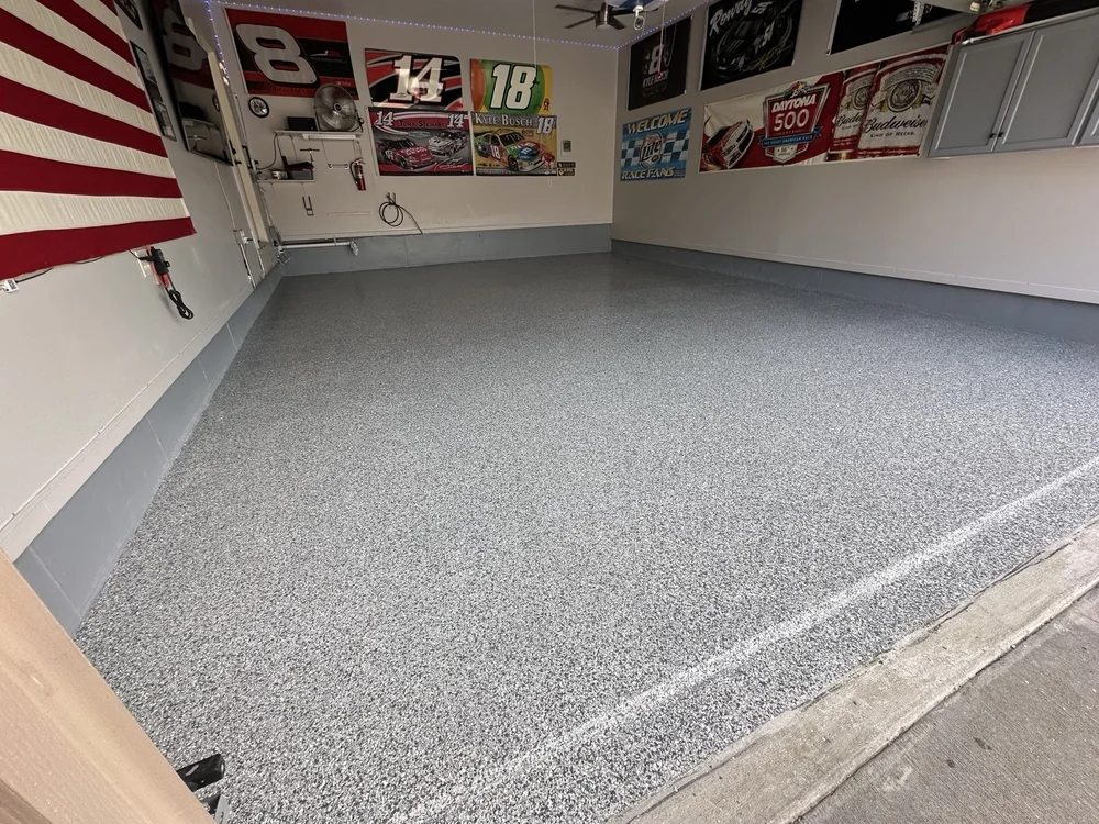 Finished decorative-chip garage floor beneath an American flag and racing memorabilia in Lee’s Summit