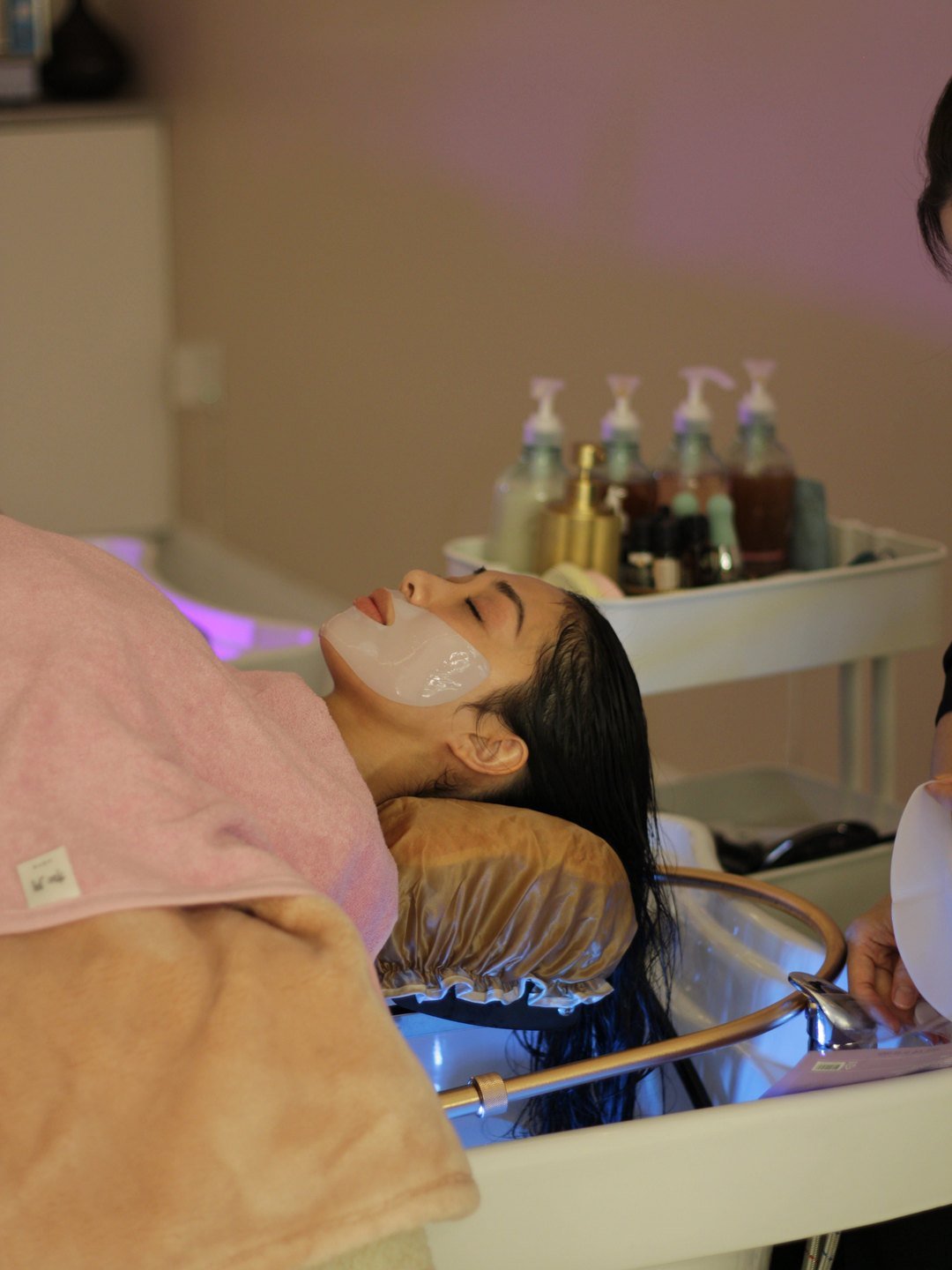 A guest resting at the head spa basin with a face mask