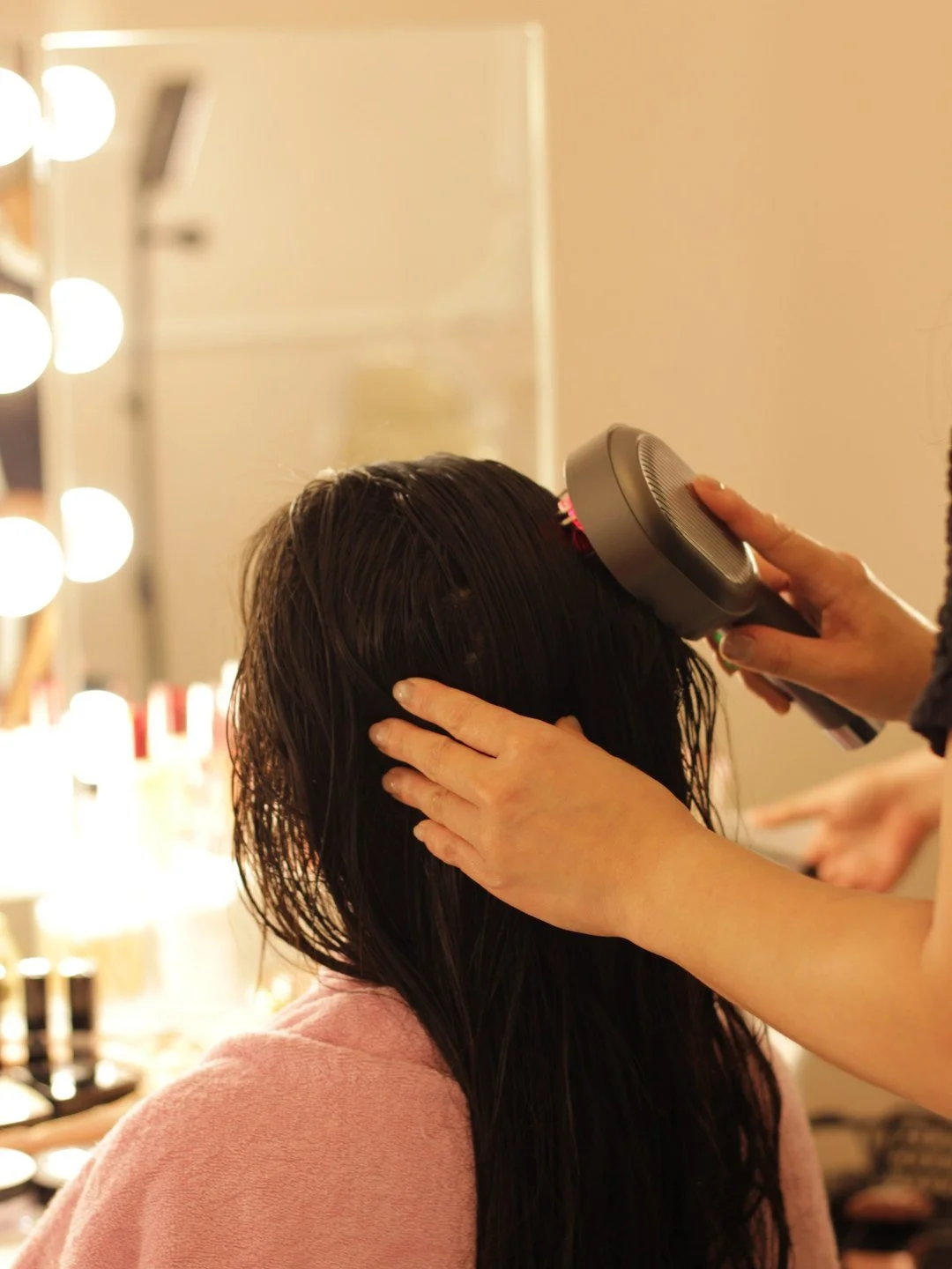 A therapist massages a guest's scalp with a handheld device