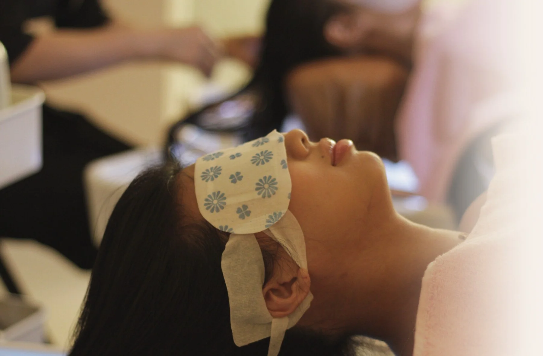 A guest resting at the head spa basin with an eye mask