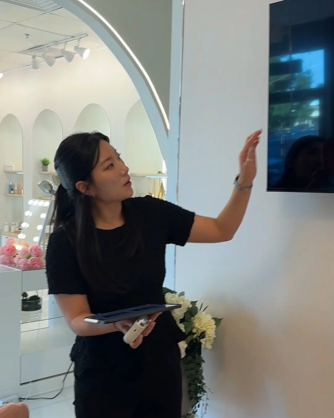 A practitioner with a tablet points to the studio's skin display
