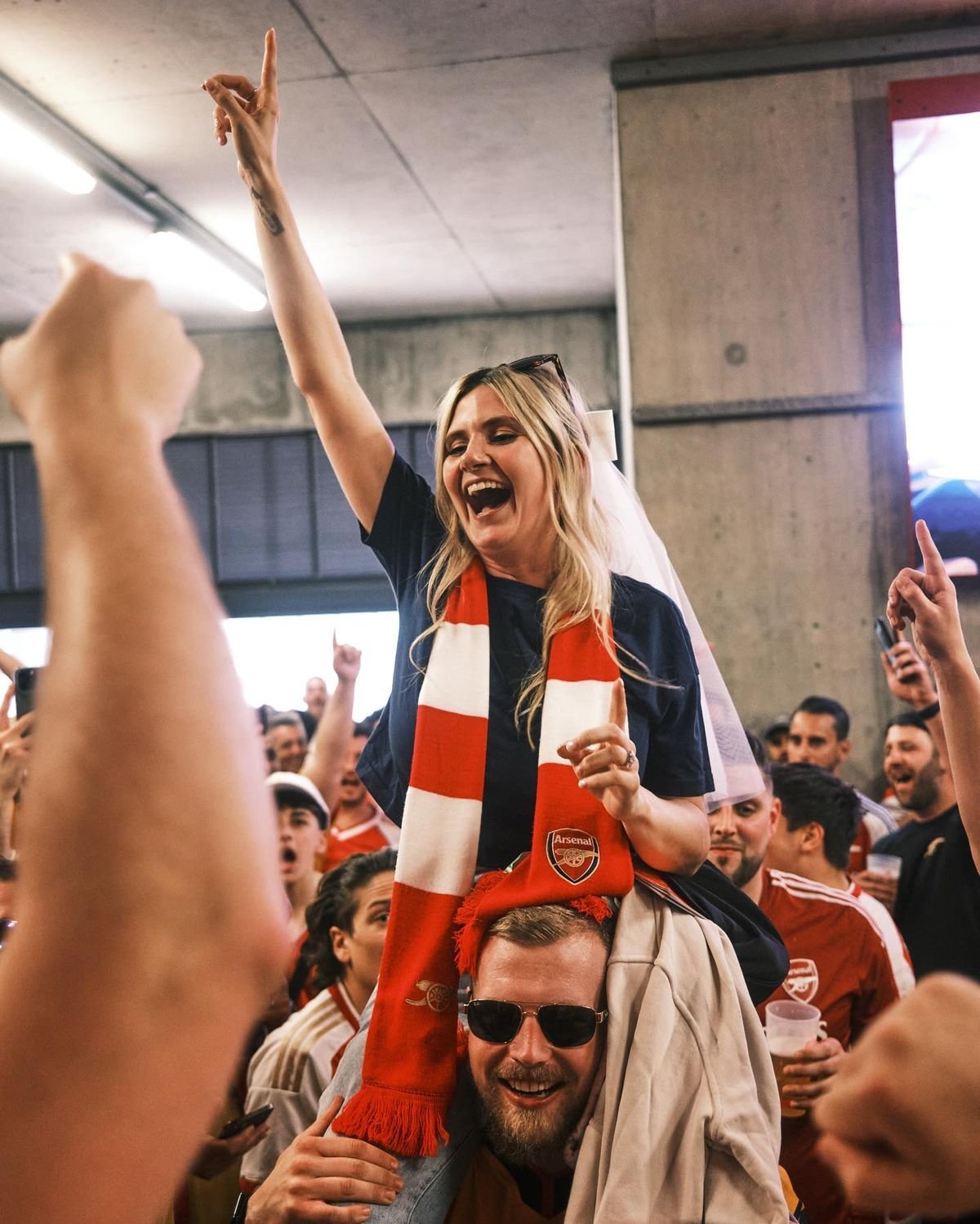 One girl wearing a jersey and soccer scarves sits on the shoulders of another fan while cheering for her team durning the World Cup