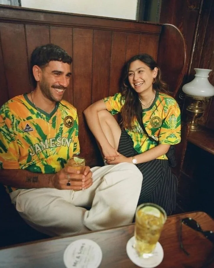 2 models in soccer jerseys drinking beer at a pub