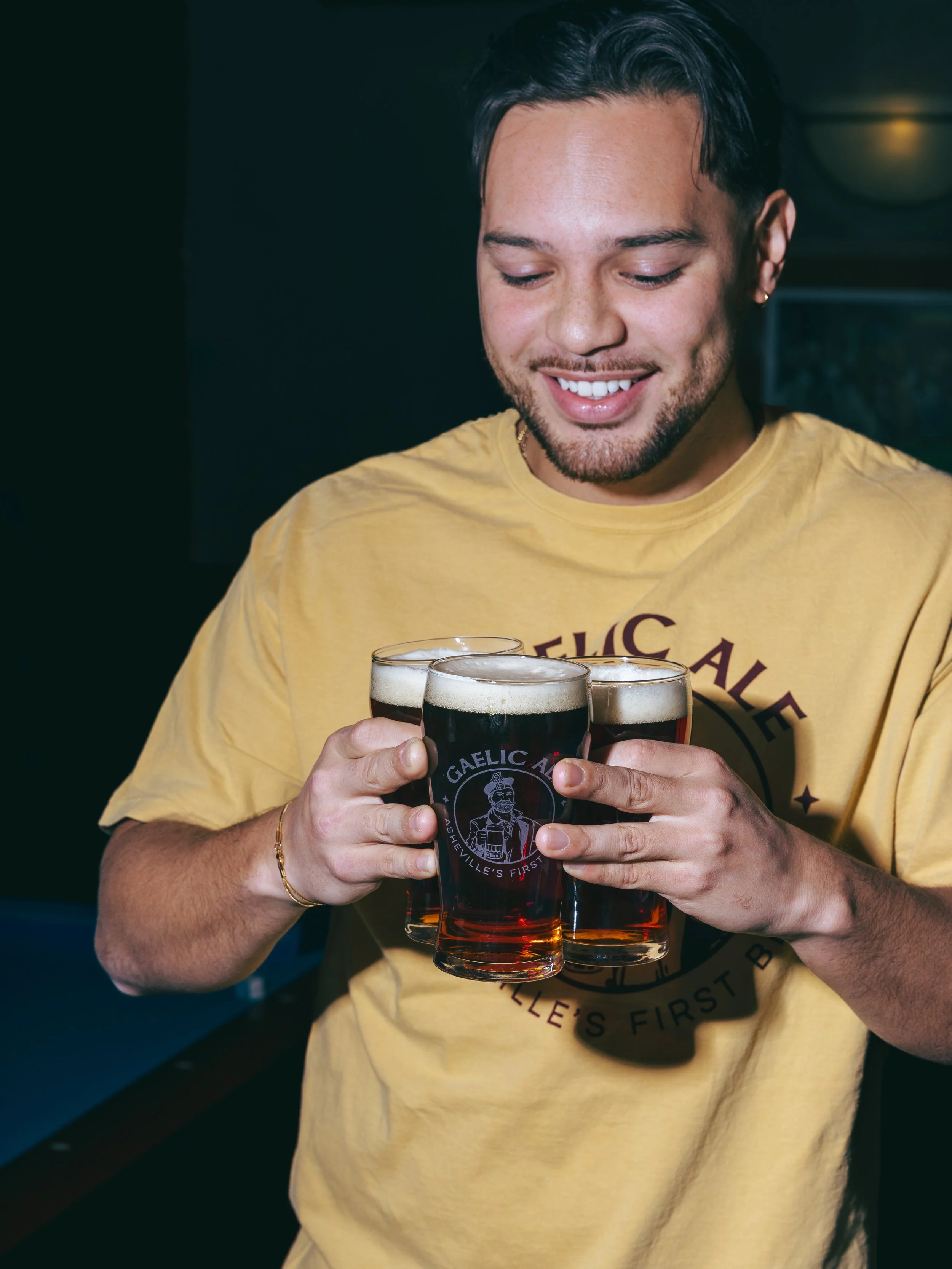 one guy carries 3 pints of Highland Brewing Gaelic Amber Ale to his friends while watching the World Cup