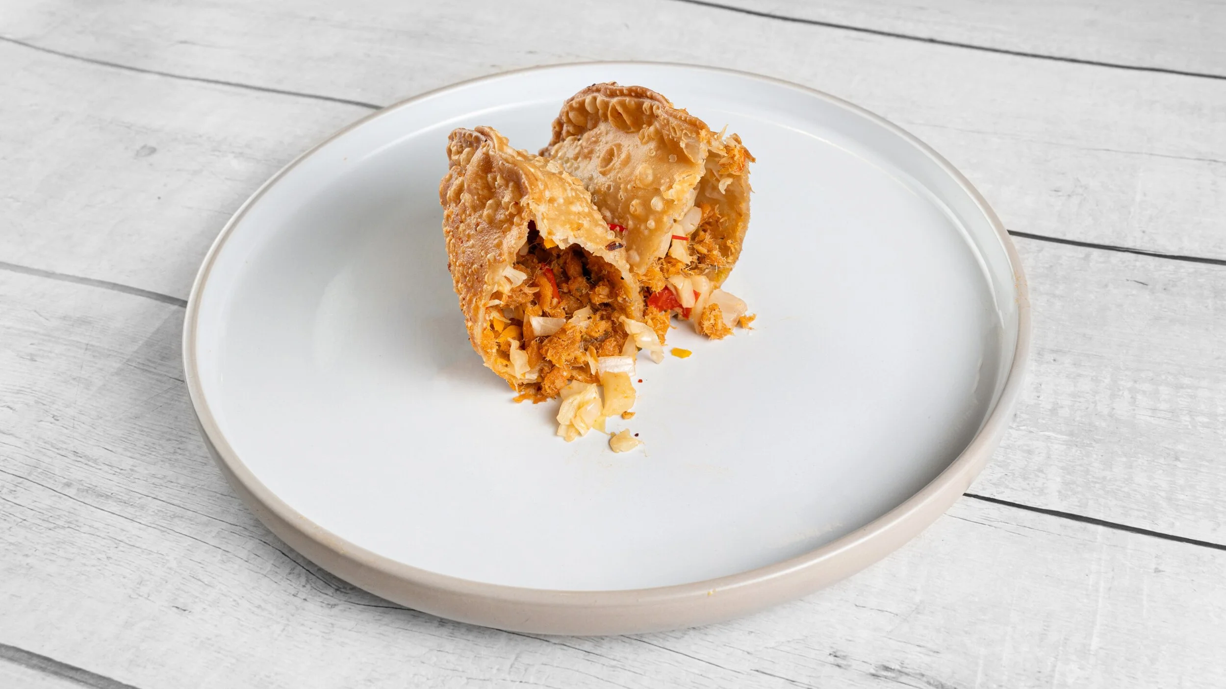 Haitian aranso patté stuffed with seasoned salted fish, onions, peppers, and cabbage inside a flaky crispy crust.