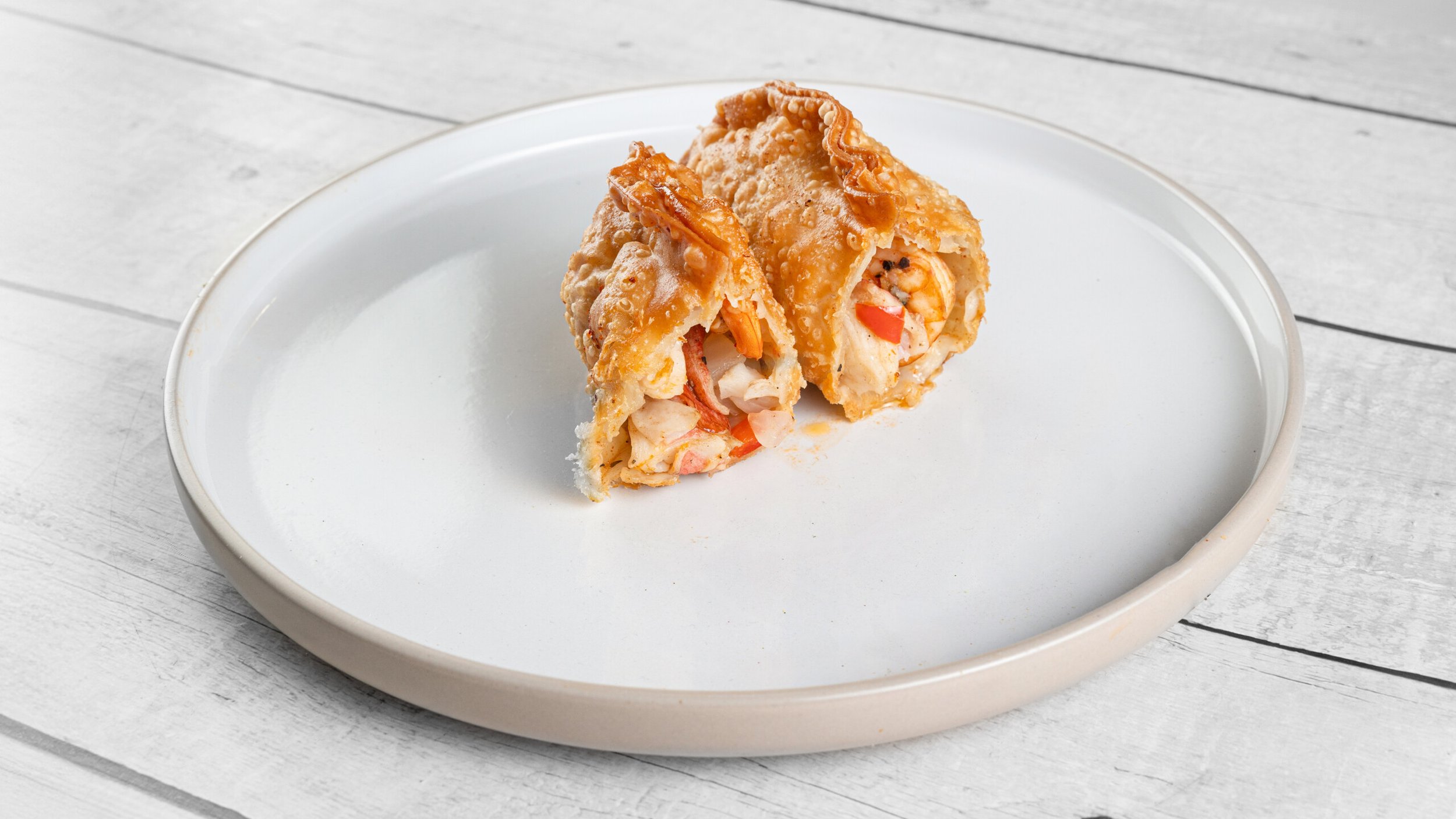 Golden fried seafood patté filled with shrimp, imitation crab, peppers, and seasoned seafood stuffing from Palate Bomb.