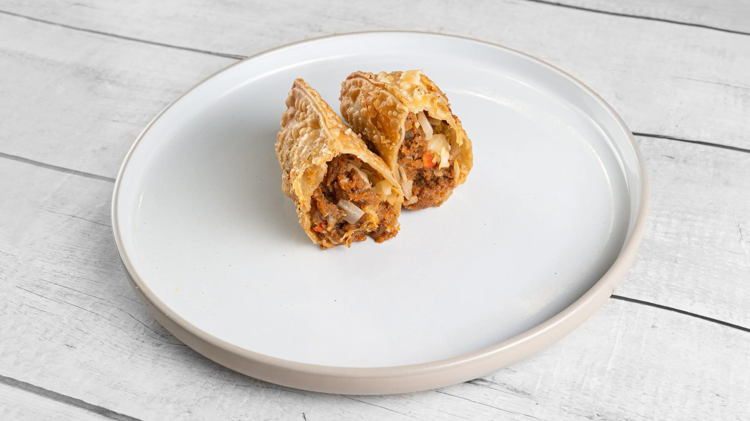 Crispy Haitian beef patté filled with seasoned ground beef, peppers, onions, cabbage, and island spices from Palate Bomb.
