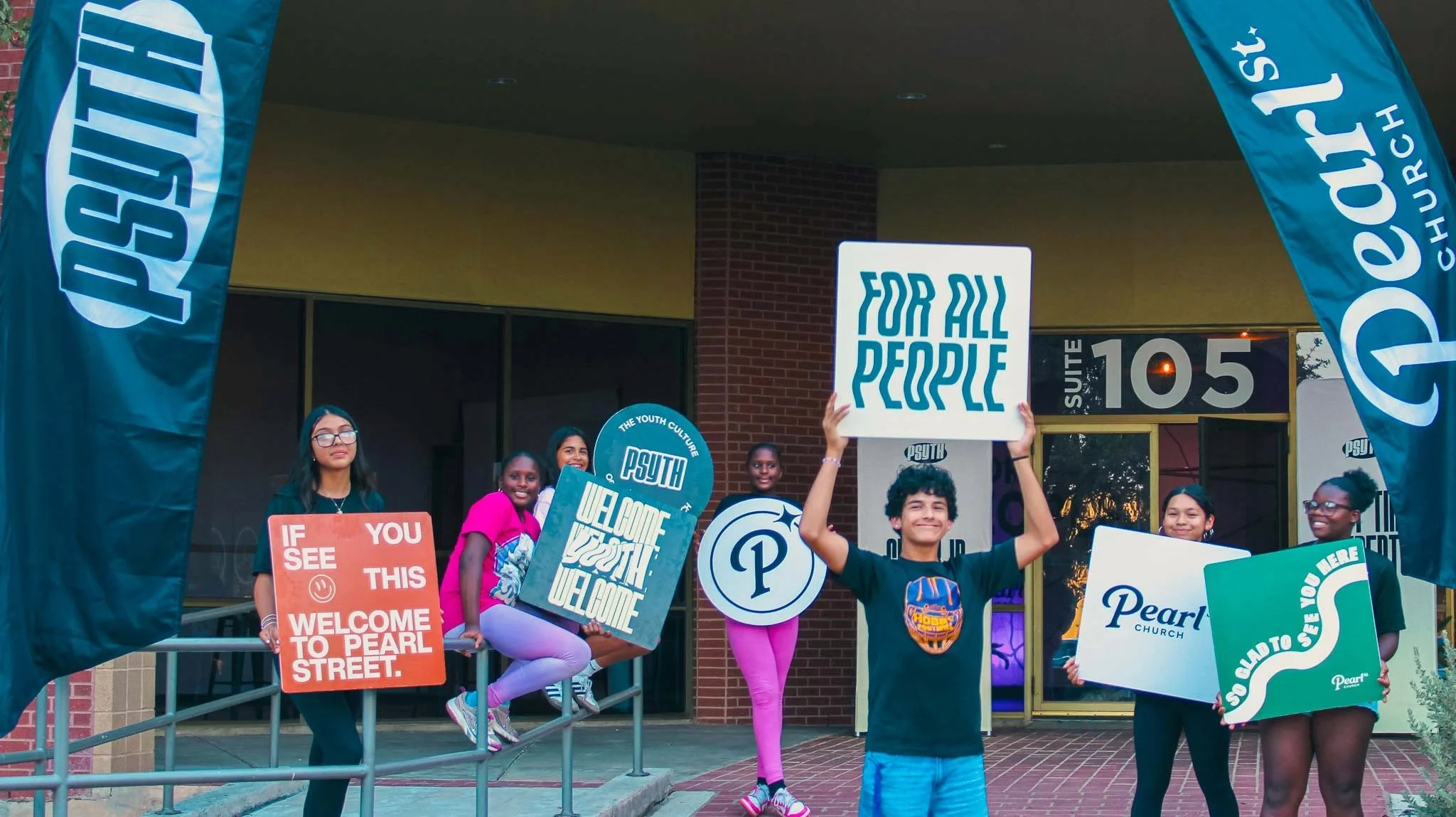 PSYTH students welcoming guests with signs outside Pearl Street Church North