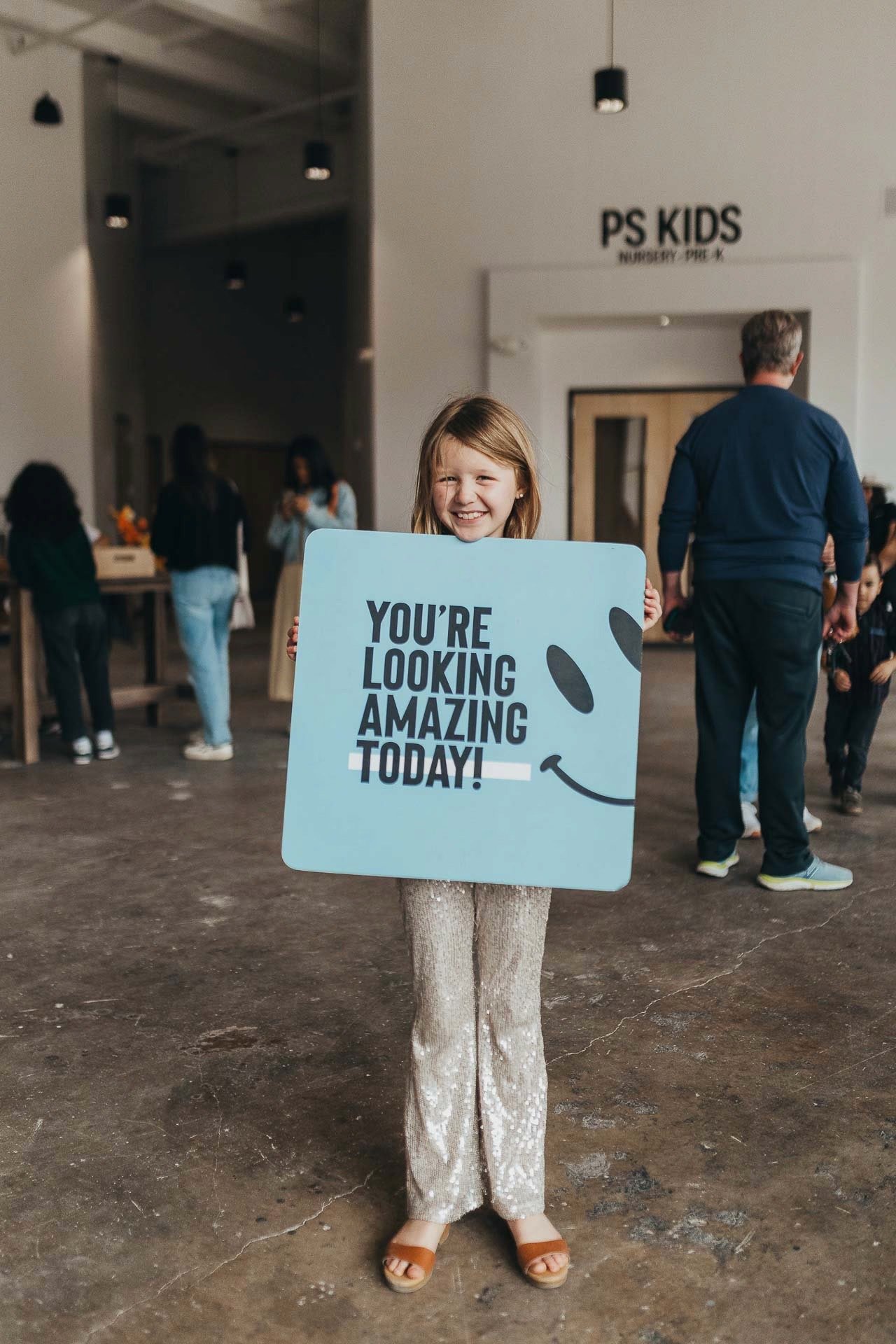 Pearl St. Kids volunteer holding a welcome sign outside the PS Kids Nursery