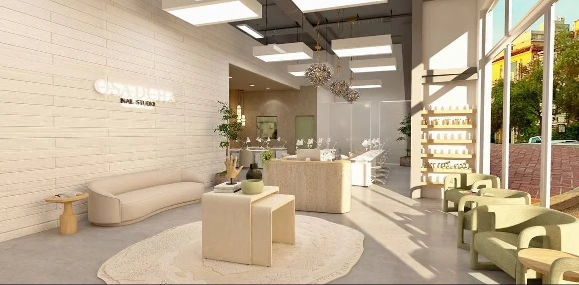 Modern and bright nail salon reception area with beige and green furniture, large windows, and plants.