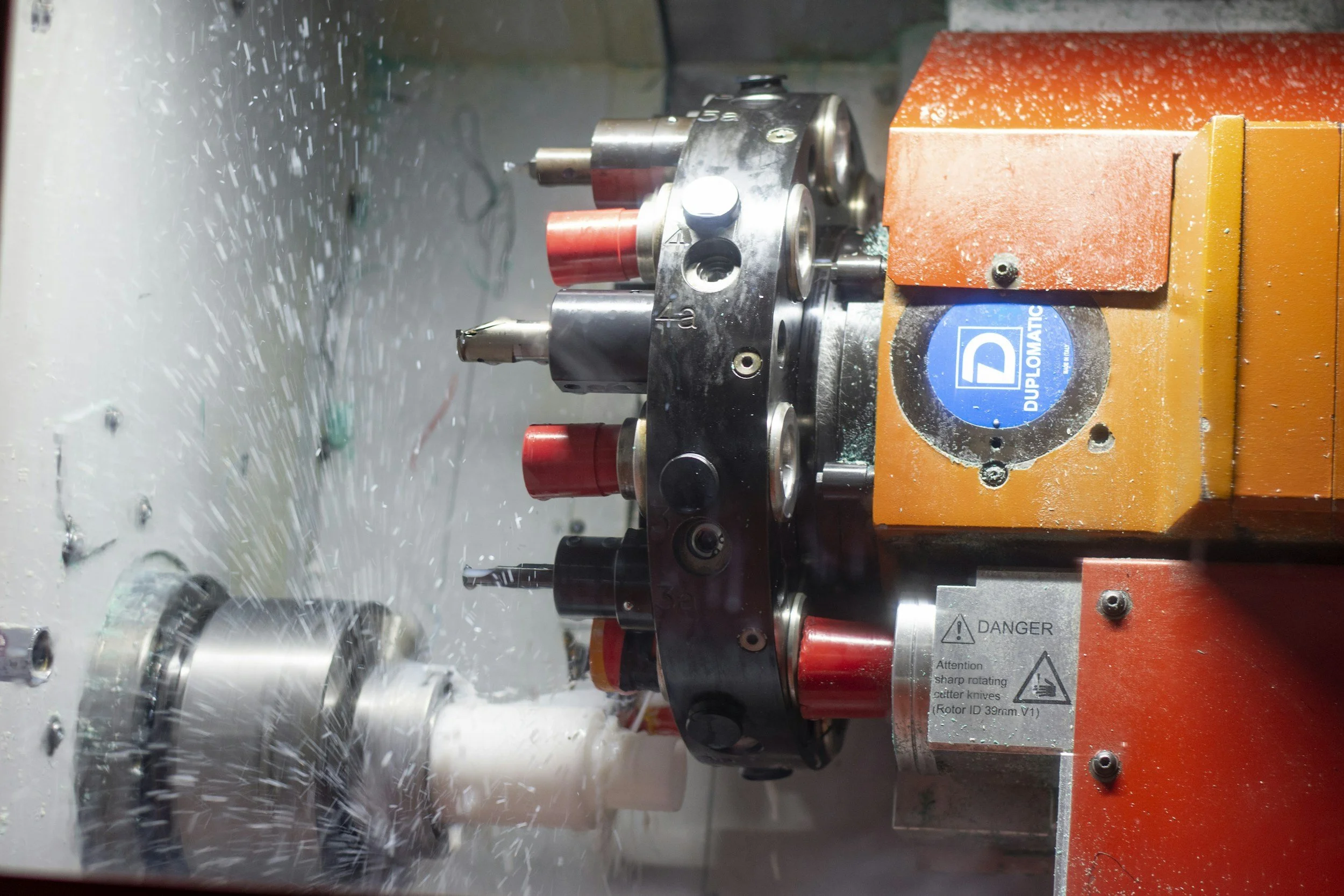 A CNC milling machine in operation with metal shavings flying off as a tool cuts metal.