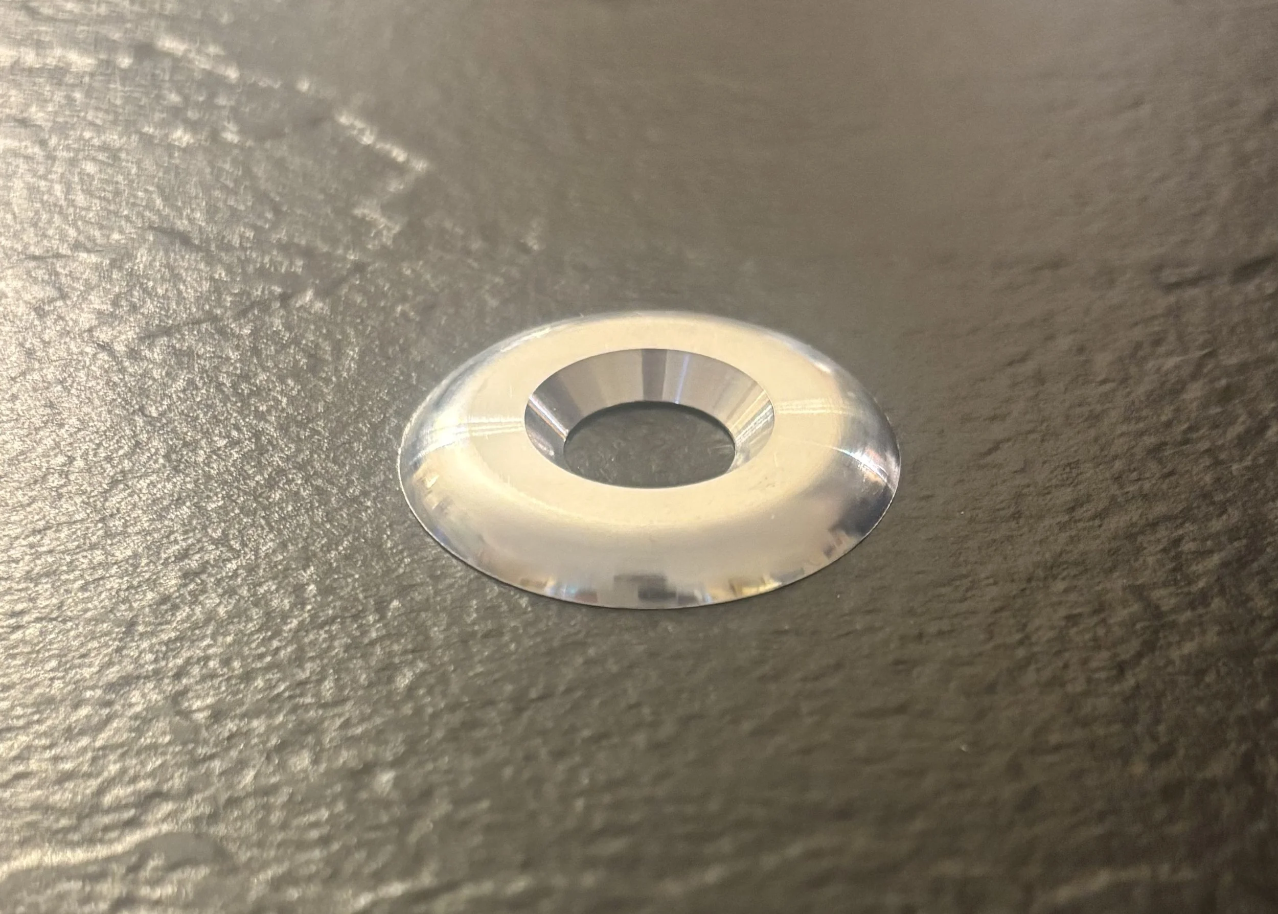 Close-up of a metallic screw or bolt head on a textured surface.