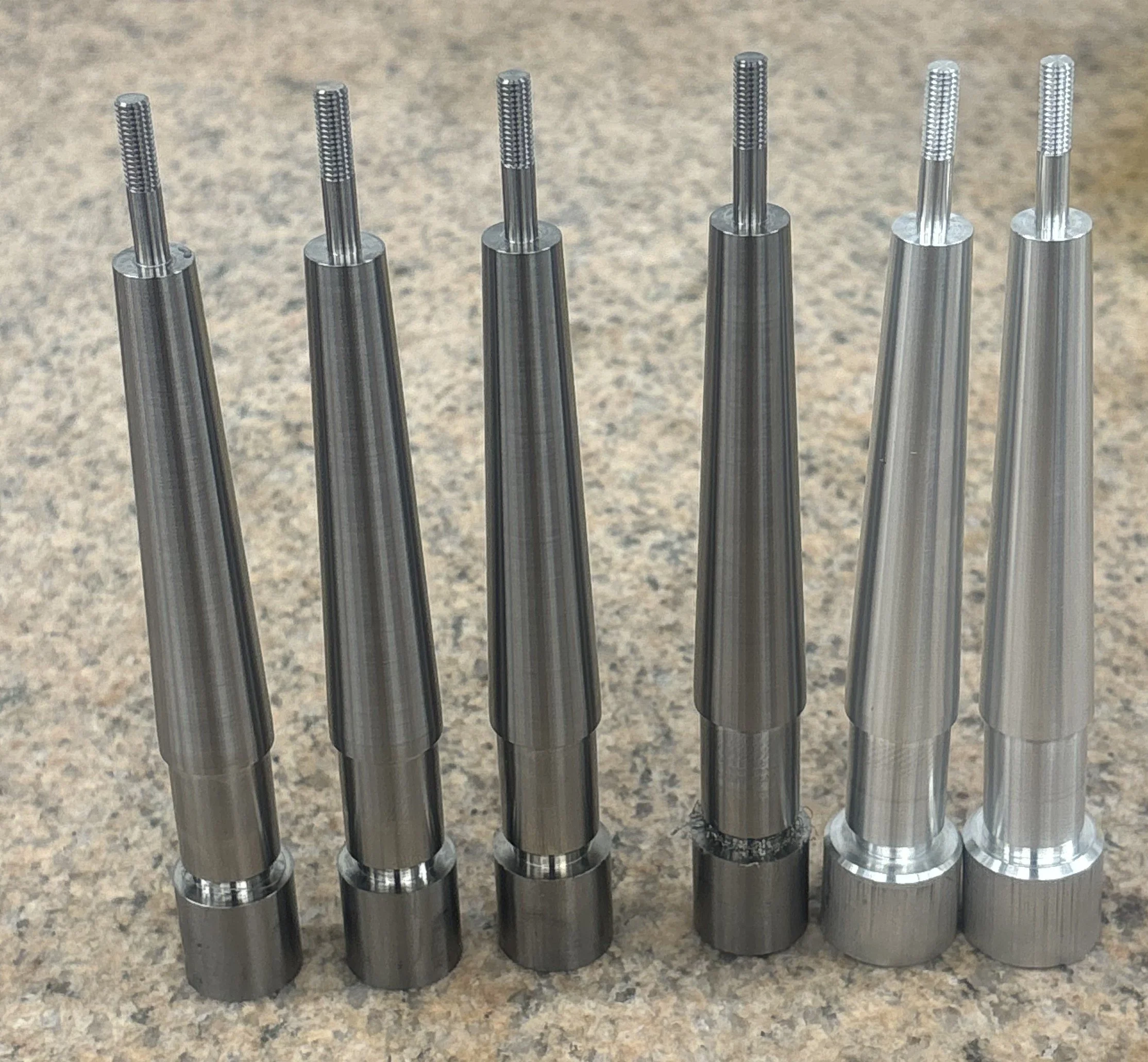 Seven metal dental or medical precision tools with textured handles, aligned vertically on a speckled countertop.