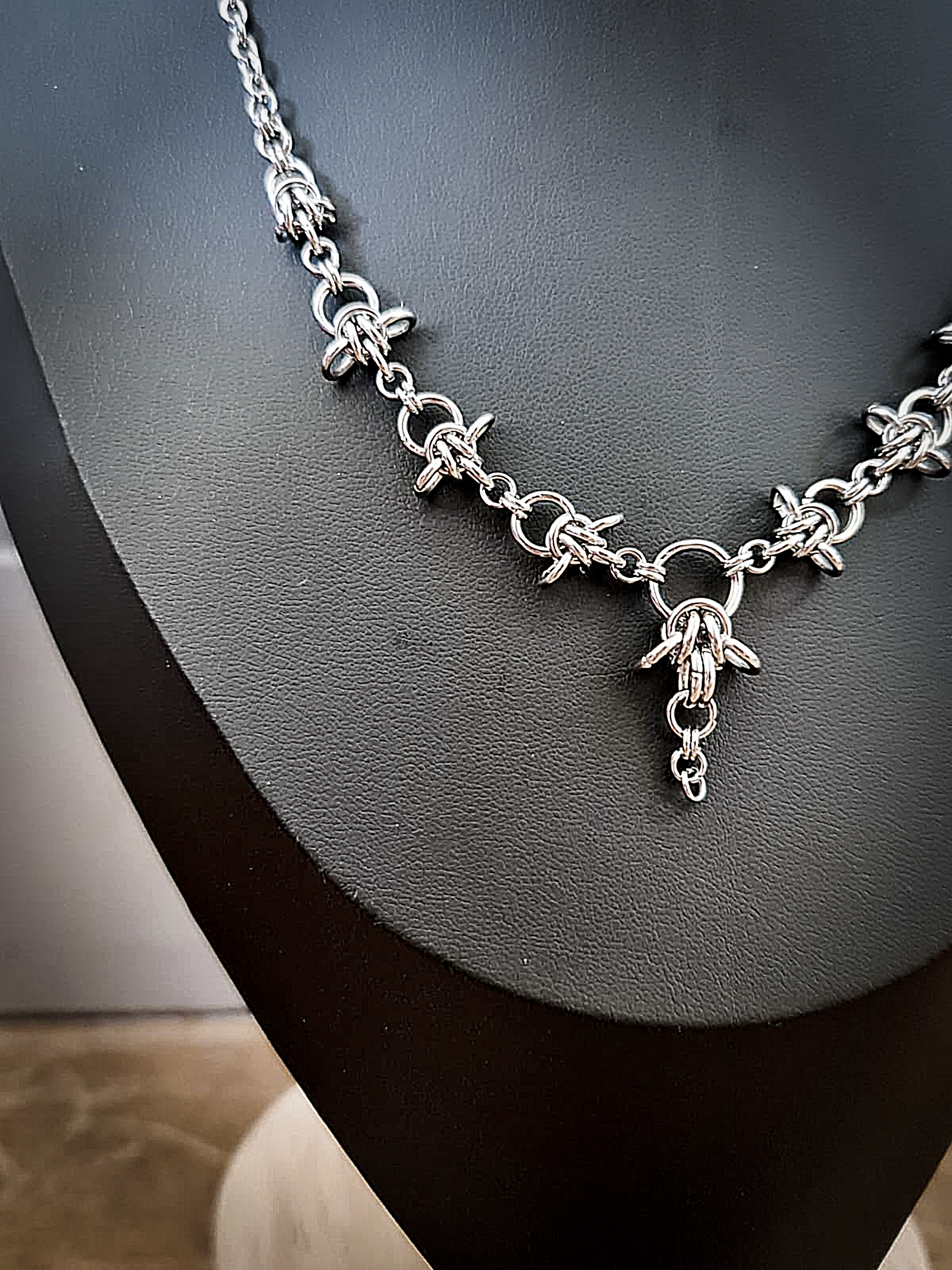 Silver necklace with charms resembling spine vertebrae, laid on a black surface.