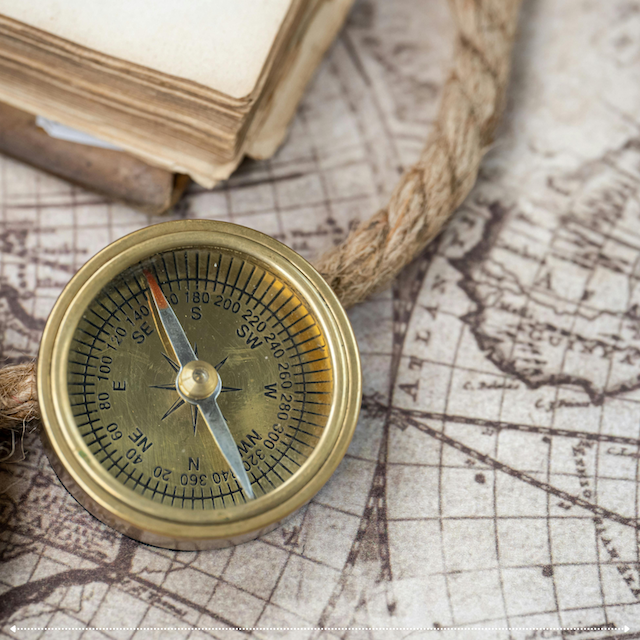 A brass compass resting on an antique map.