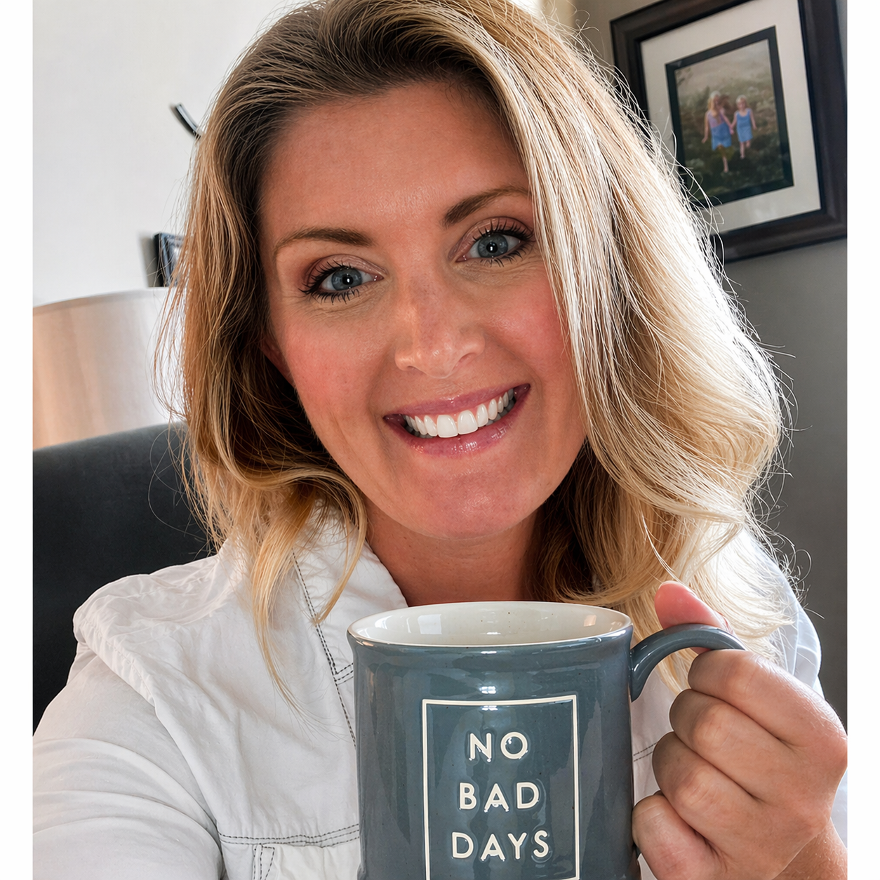 A woman smiling and holding a mug that says 'NO BAD DAYS'.