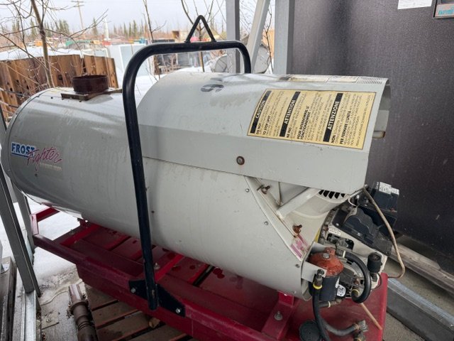 Large white heating oil tank on a red metal cart and attached hoses.