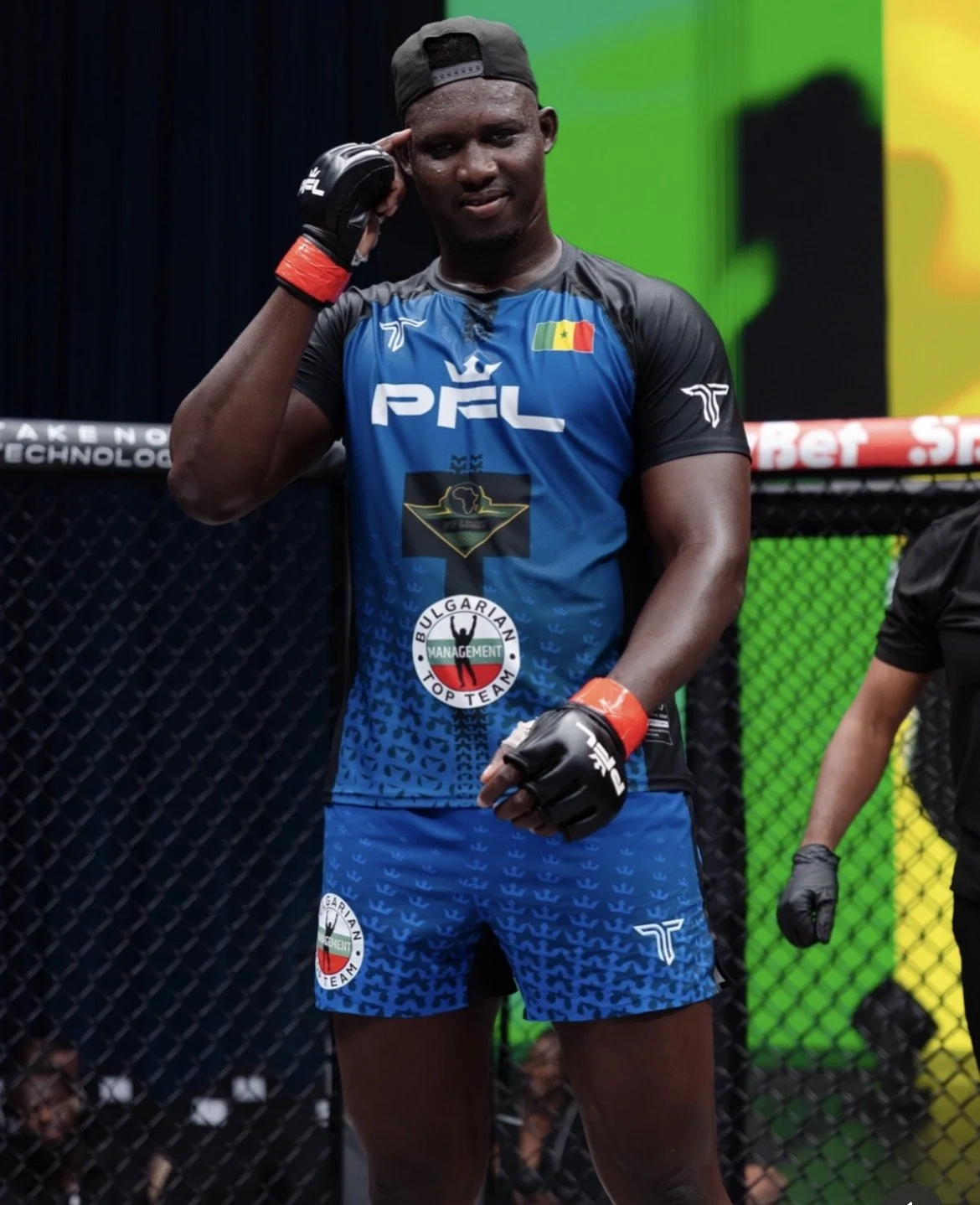 Abdul Kane Posing for a photo in a MMA cage while wearing a PFL x No Limit Sports t-shirt