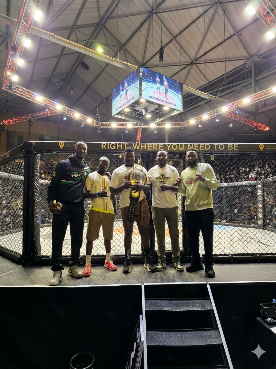 A group of five men standing in front of an MMA cage under stadium lights; the central figure holds a championship belt, and team members are seen wearing No Limit Sports branded t-shirts and apparel.