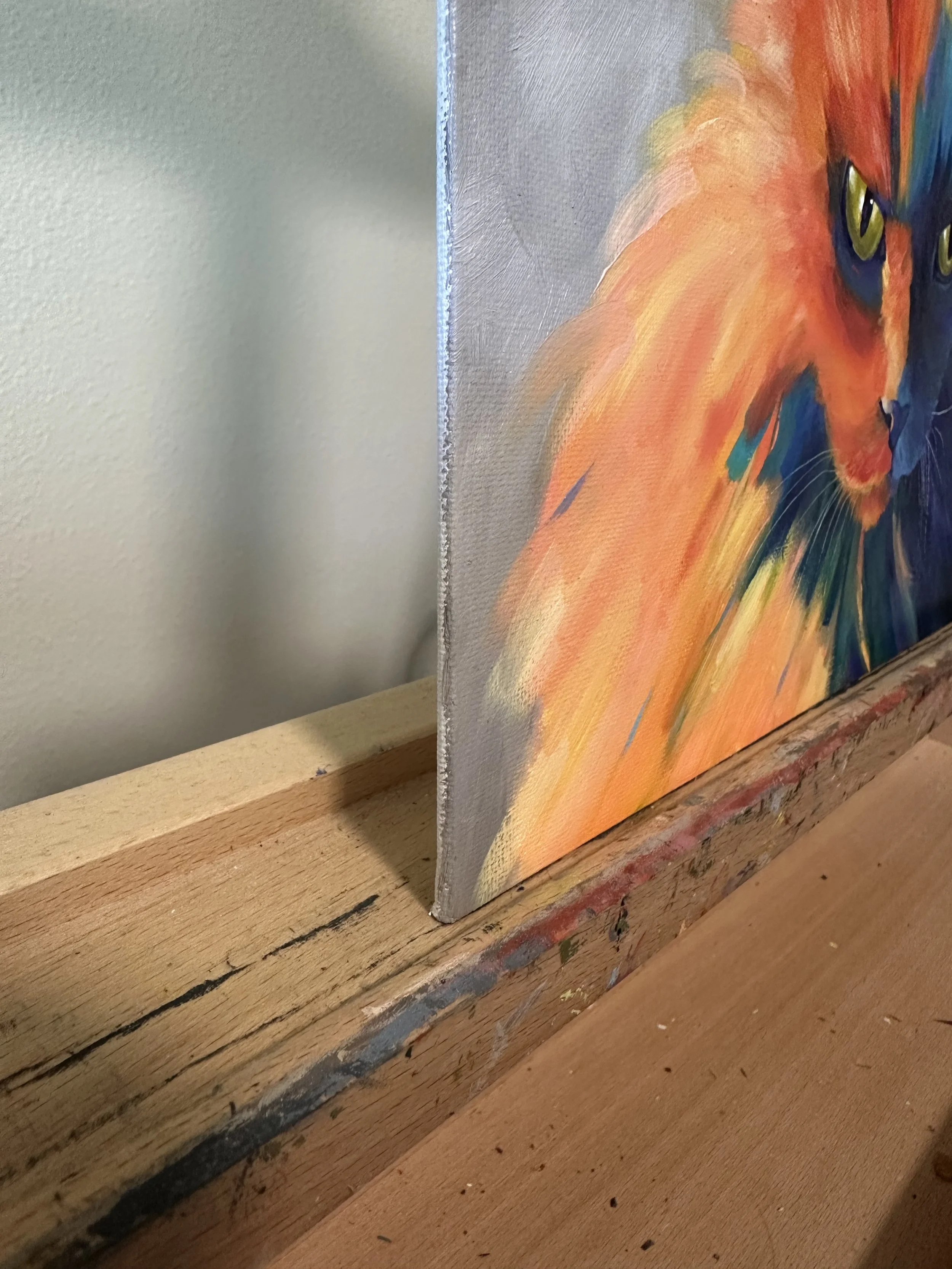 The side edge of an oil painting of a cat done in warm and cool colors.