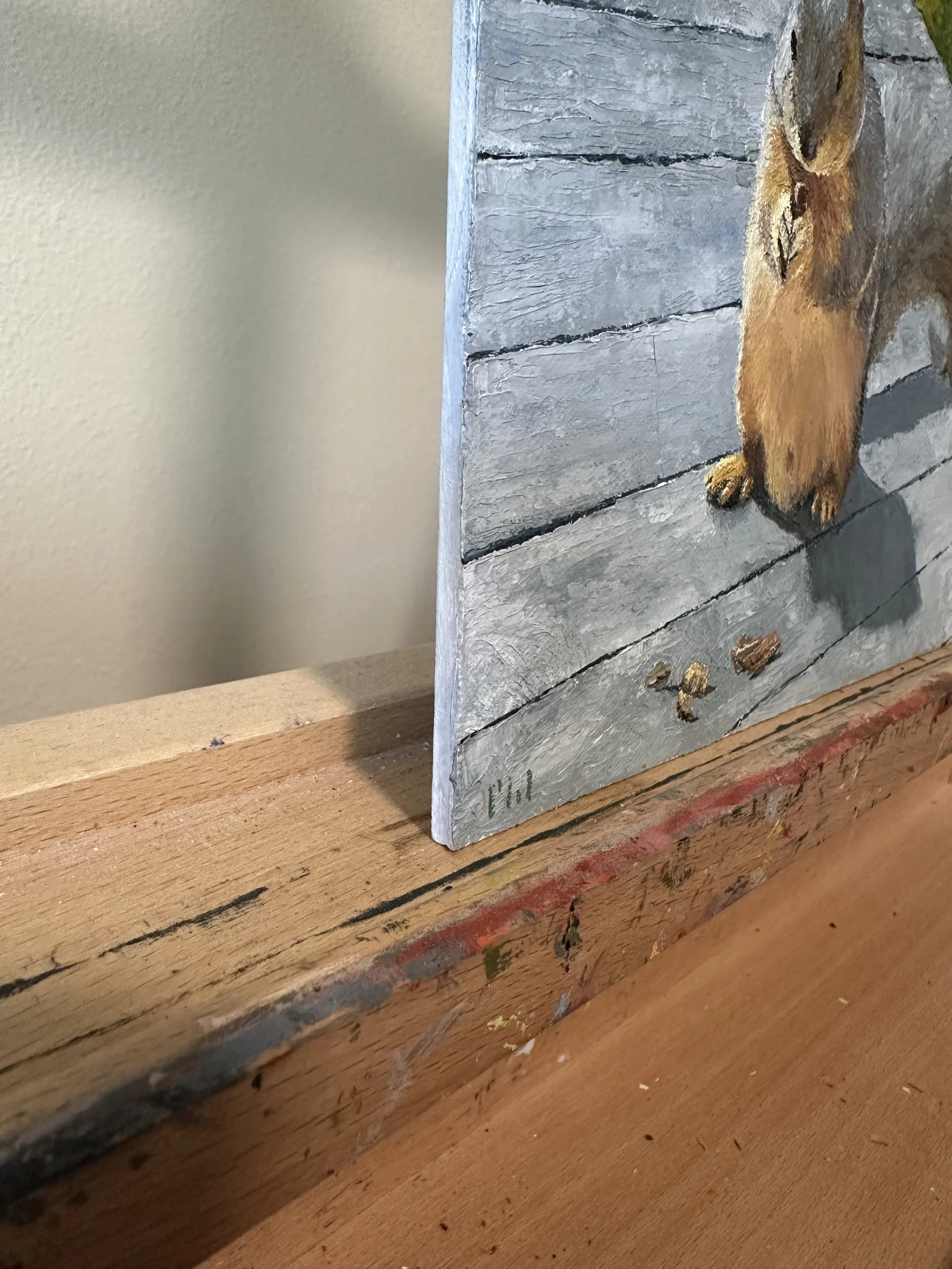 A photograph showing the side edge of a palette knife oil painting of a squirrel eating a pecan.