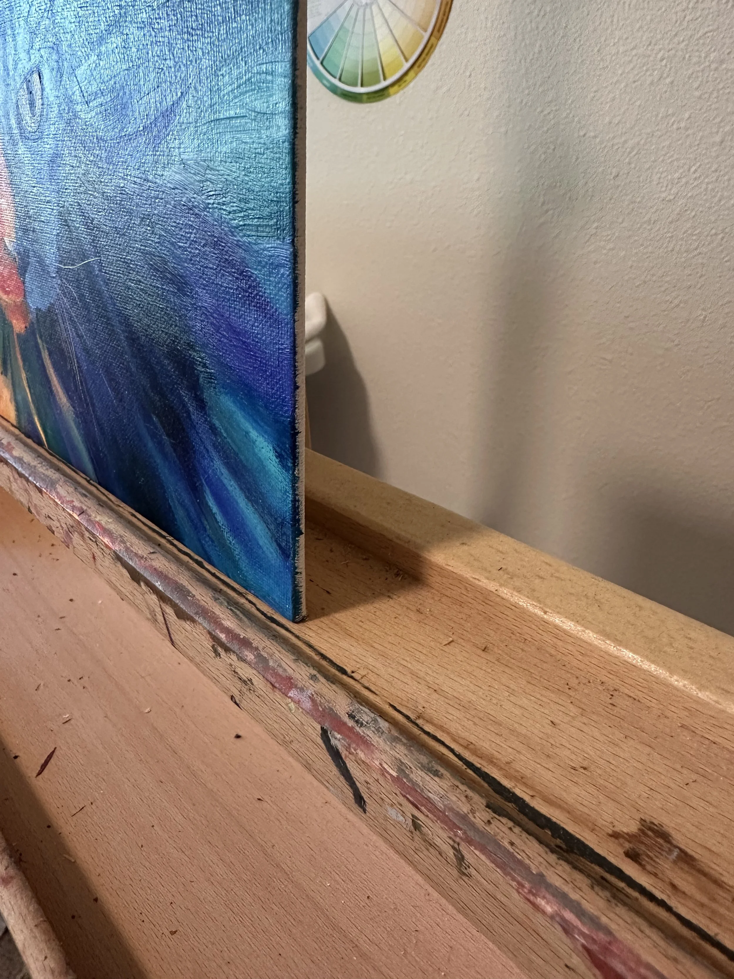 The side edge of the canvas of an oil painting of a cat done in warm and cool colors.