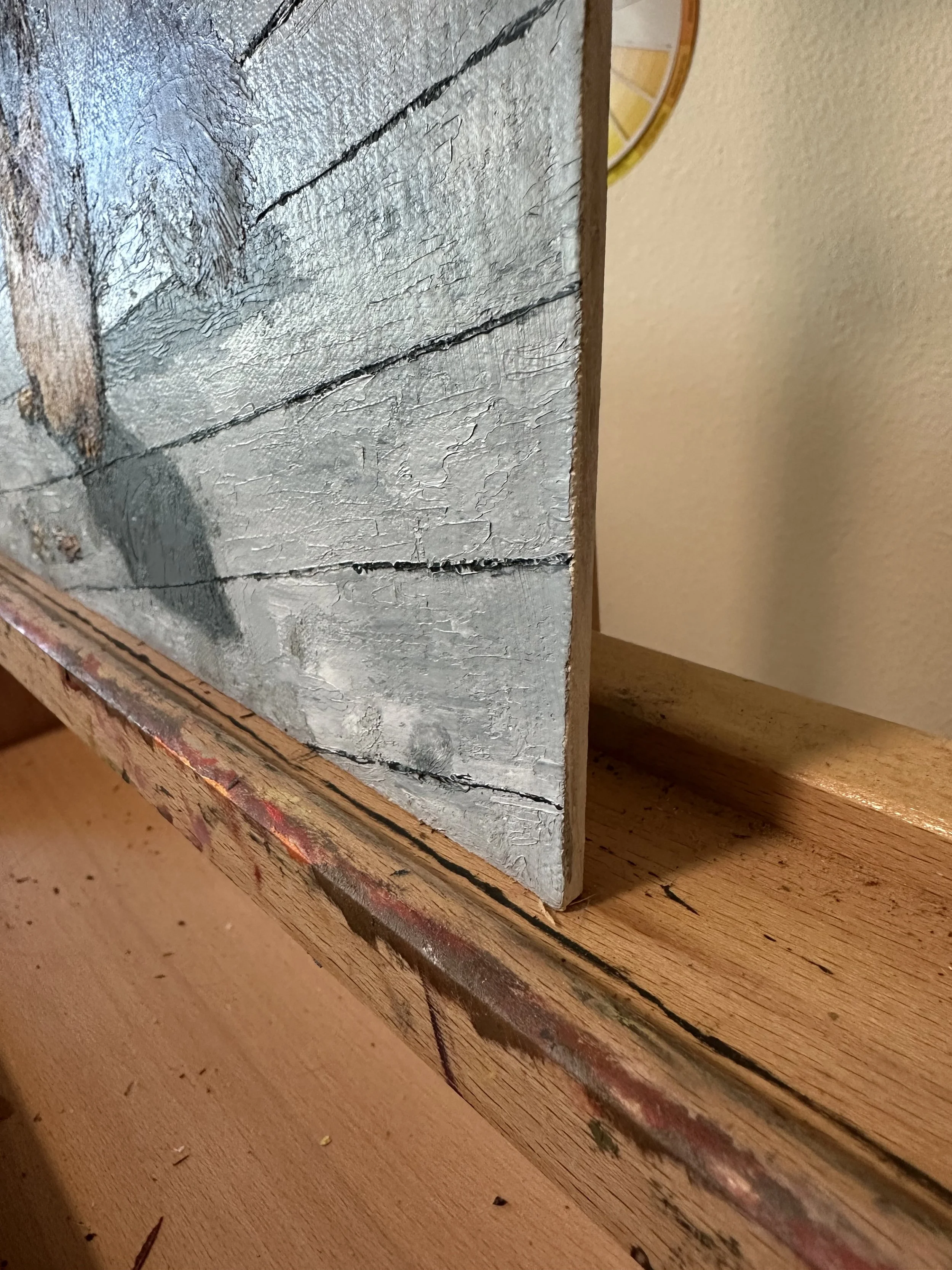 A photograph showing the side edge of a palette knife oil painting of a squirrel eating a pecan.