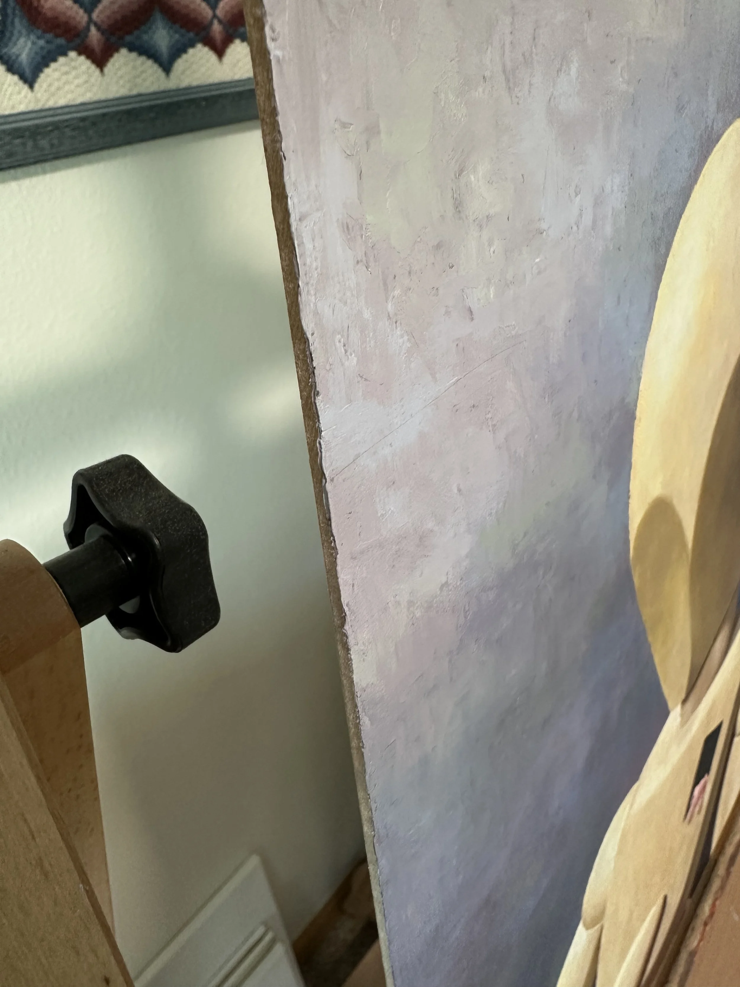 The canvas edge of a palette knife oil painting of a wooden doll looking down at a pink stuffed rabbit.
