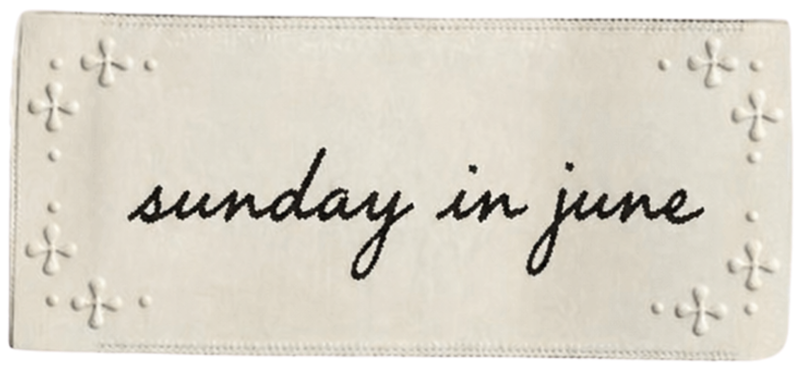 A white card with embossed decorative patterns on the top left and bottom right corners, and the handwritten phrase "sunday in june" in black ink in the center.