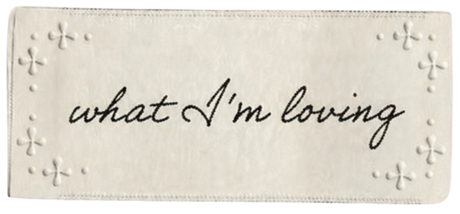 A white card with embossed floral designs in the corners and the handwritten phrase 'what I'm loving' in the center.