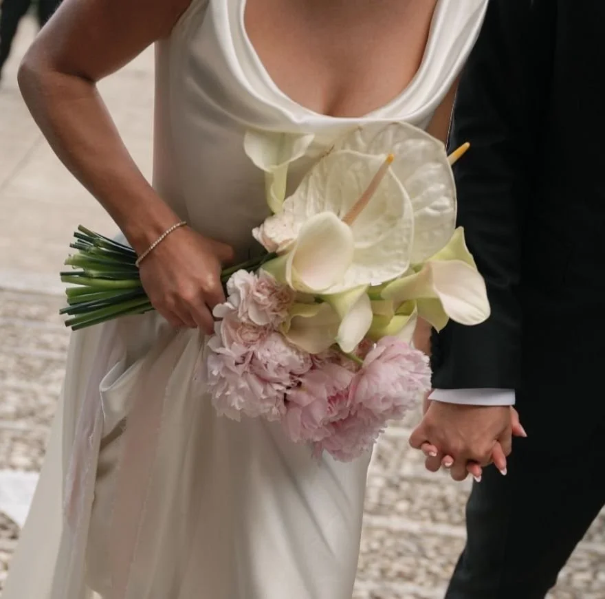 Bride and groom holding hands, bride holding a bouquet of white and pink flowers