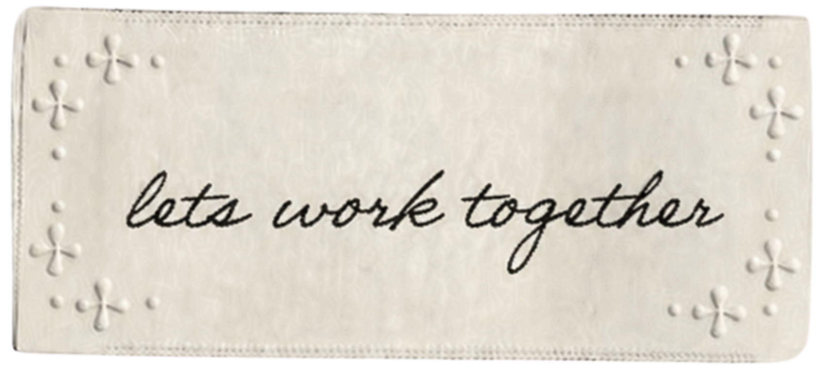Embossed white rectangular plaque with decorative borders and the handwritten phrase "lets work together" in black ink.