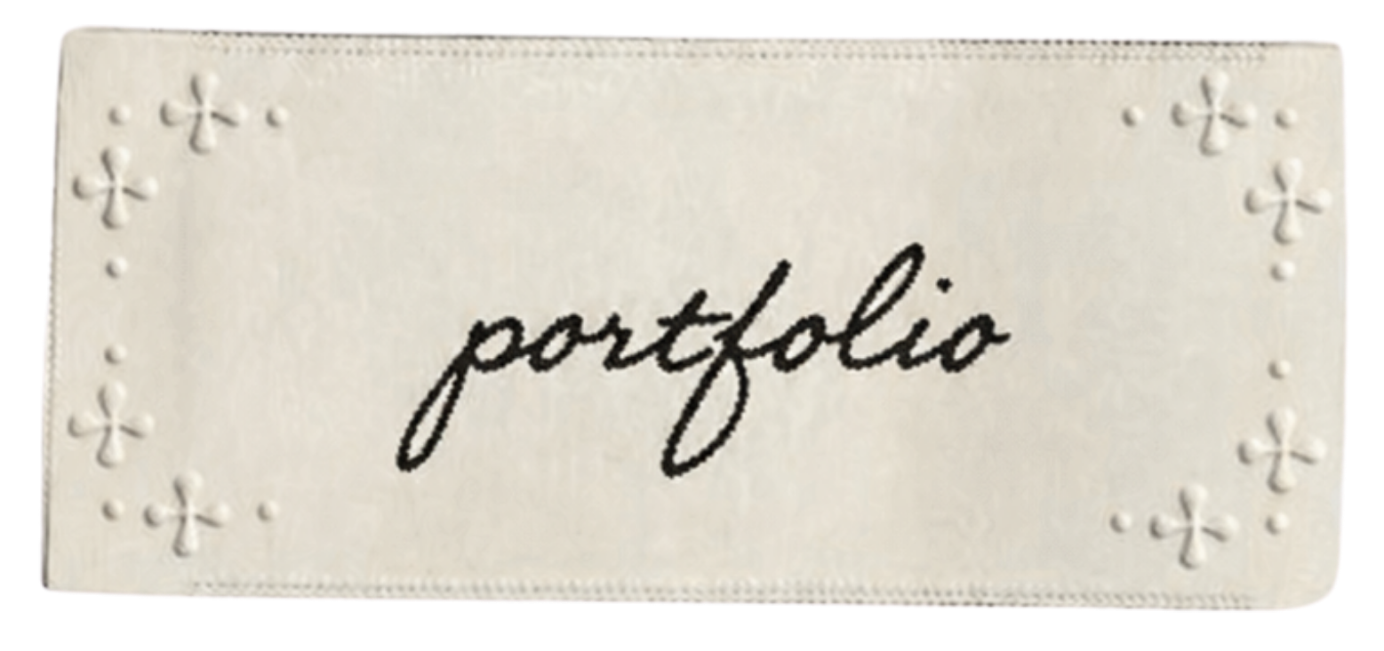 A white planner or card with the word "portfolio" written in black cursive font, decorated with small embossed flower patterns on the borders.
