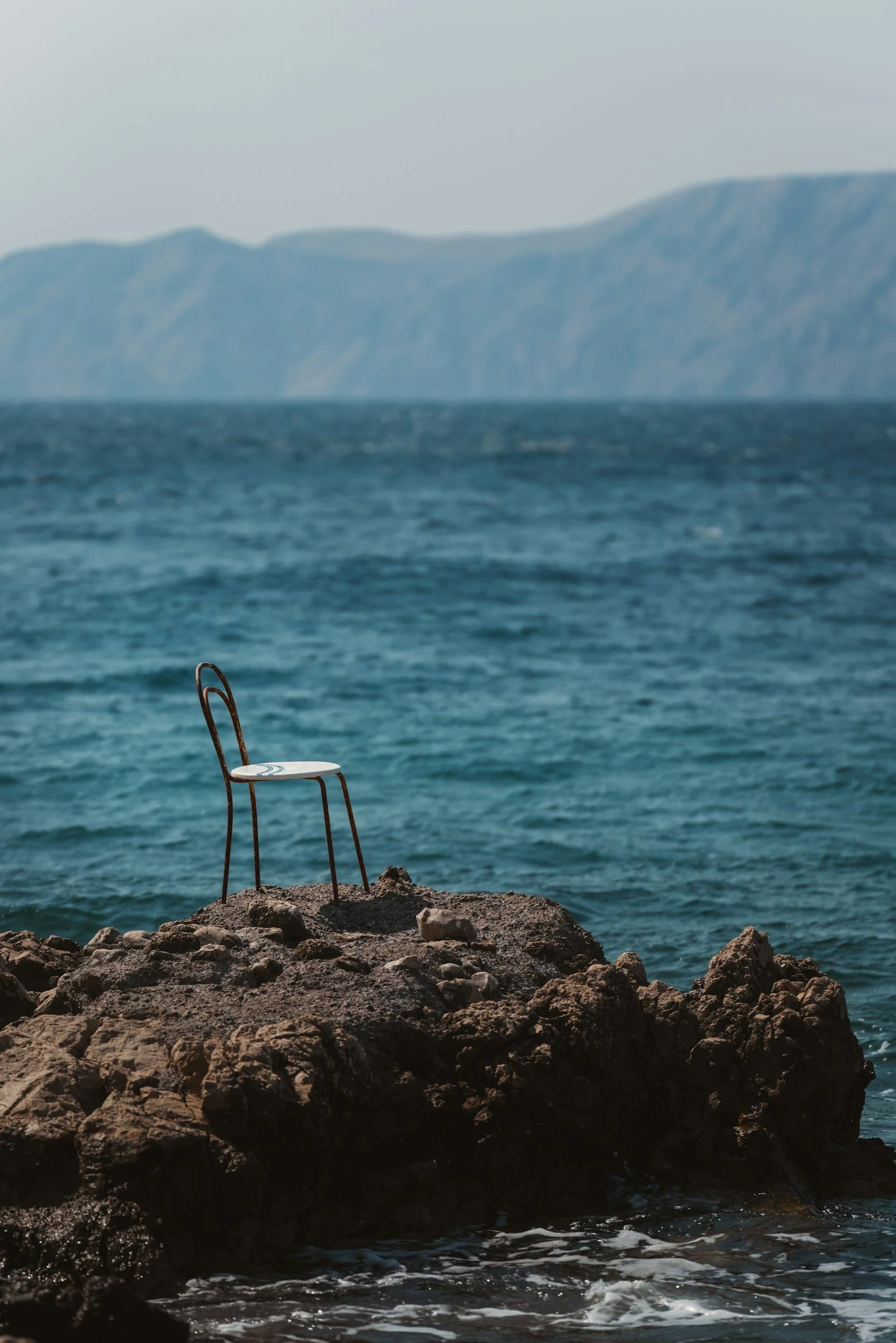 Chair sitting on rocks on a coastal jetty near ocean waves