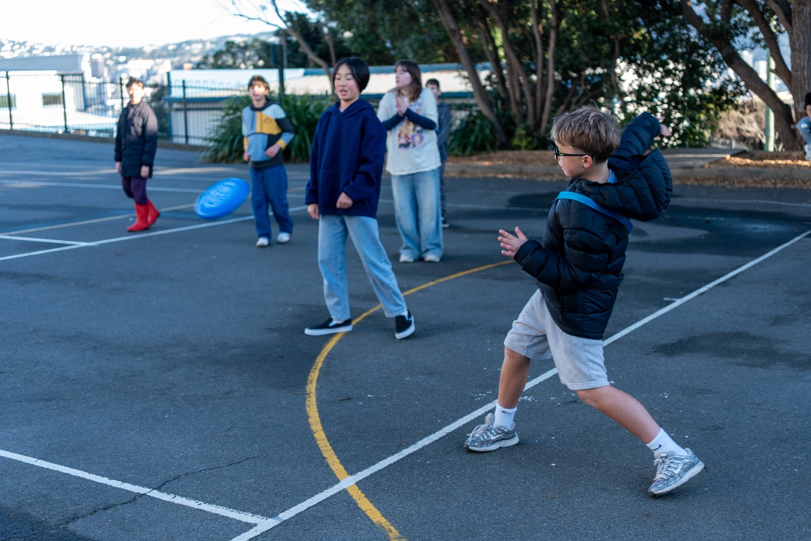 Children playing with a frisbee on a court outdoors.