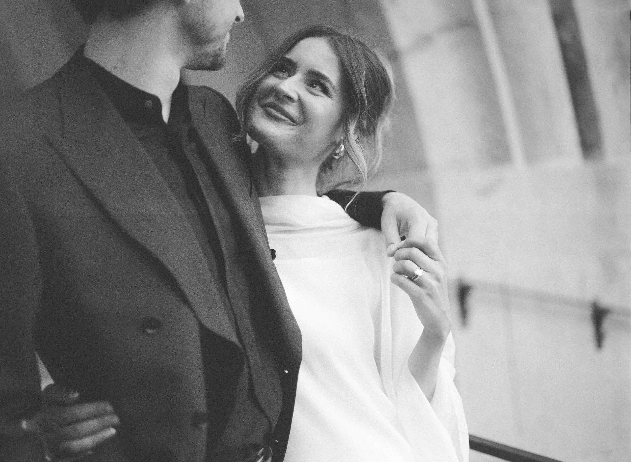 A black-and-white photo of a man and a woman sharing an intimate moment, with the woman looking up at the man and smiling.