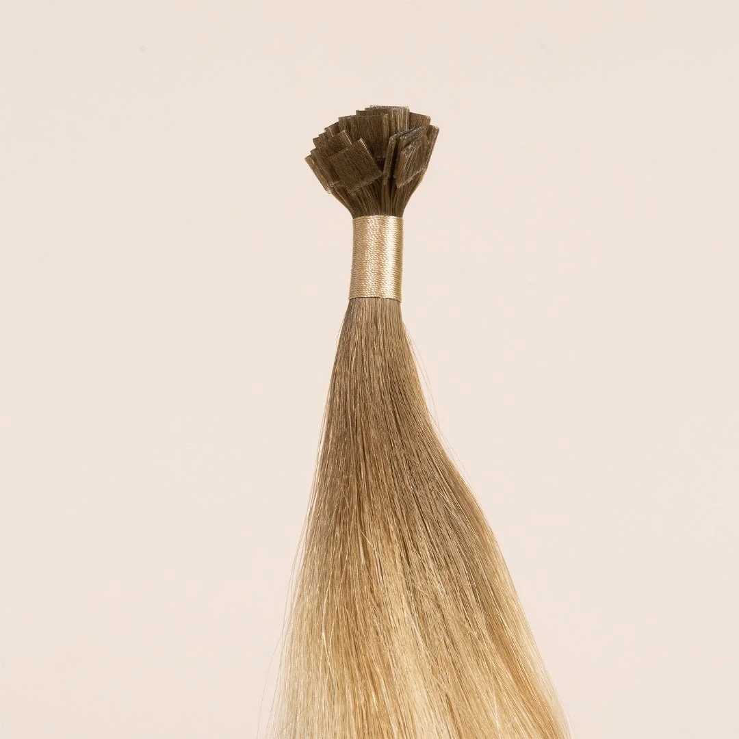 A bundle of blonde hair extensions with a gold band at the top, set against a plain light background.